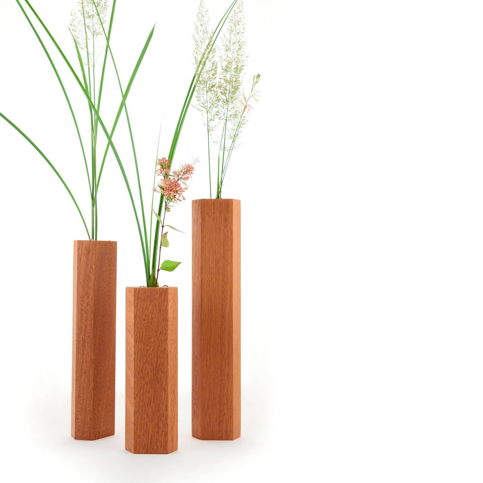Description: Crafted from solid wood with a glass tube insert. The three different sized blocks come together to create a dynamic composition, playing off each other's facets. the Bloc single-bud vase is hexagonally shaped with facets that absorb