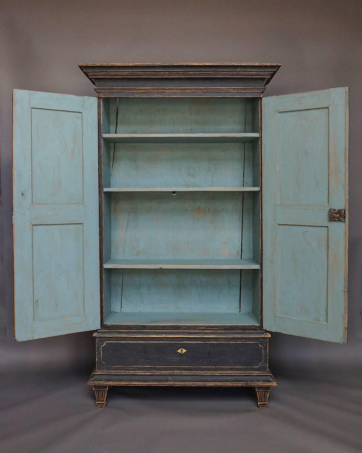 Gustavian cabinet, Sweden, circa 1800, with bold cornice, two full height doors with reeded panels, and single drawer at the bottom. Three interior shelves. Tapering square feet with carved detail. A rare find.