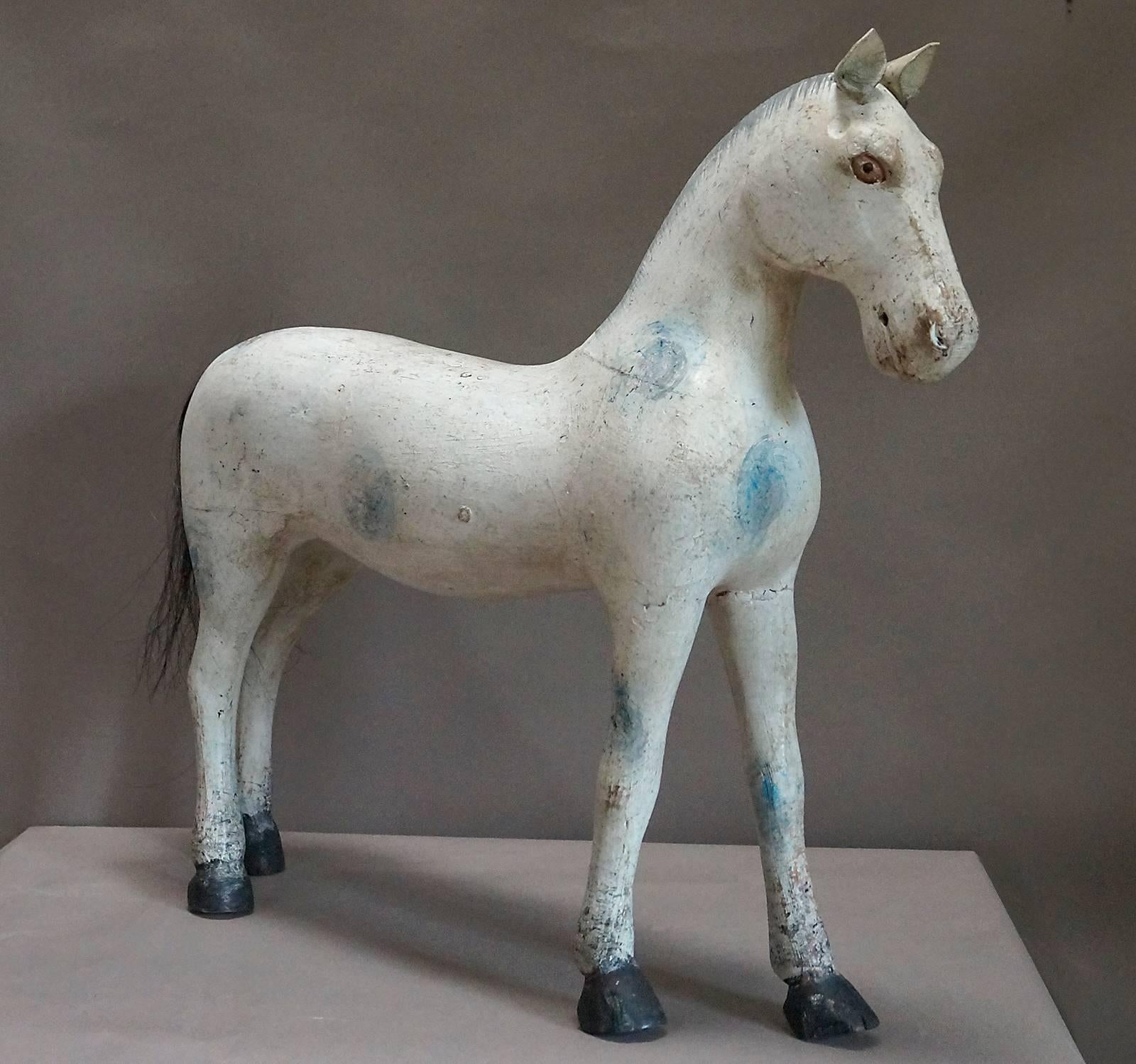 Carved horse, circa 1870, from the famous toy factory in Gemla, Småland, in southern Sweden. His white coat is decorated with faded blue spots, and his eyes are painted an amber color. Leather ears, painted mane, and real horse hair tail.