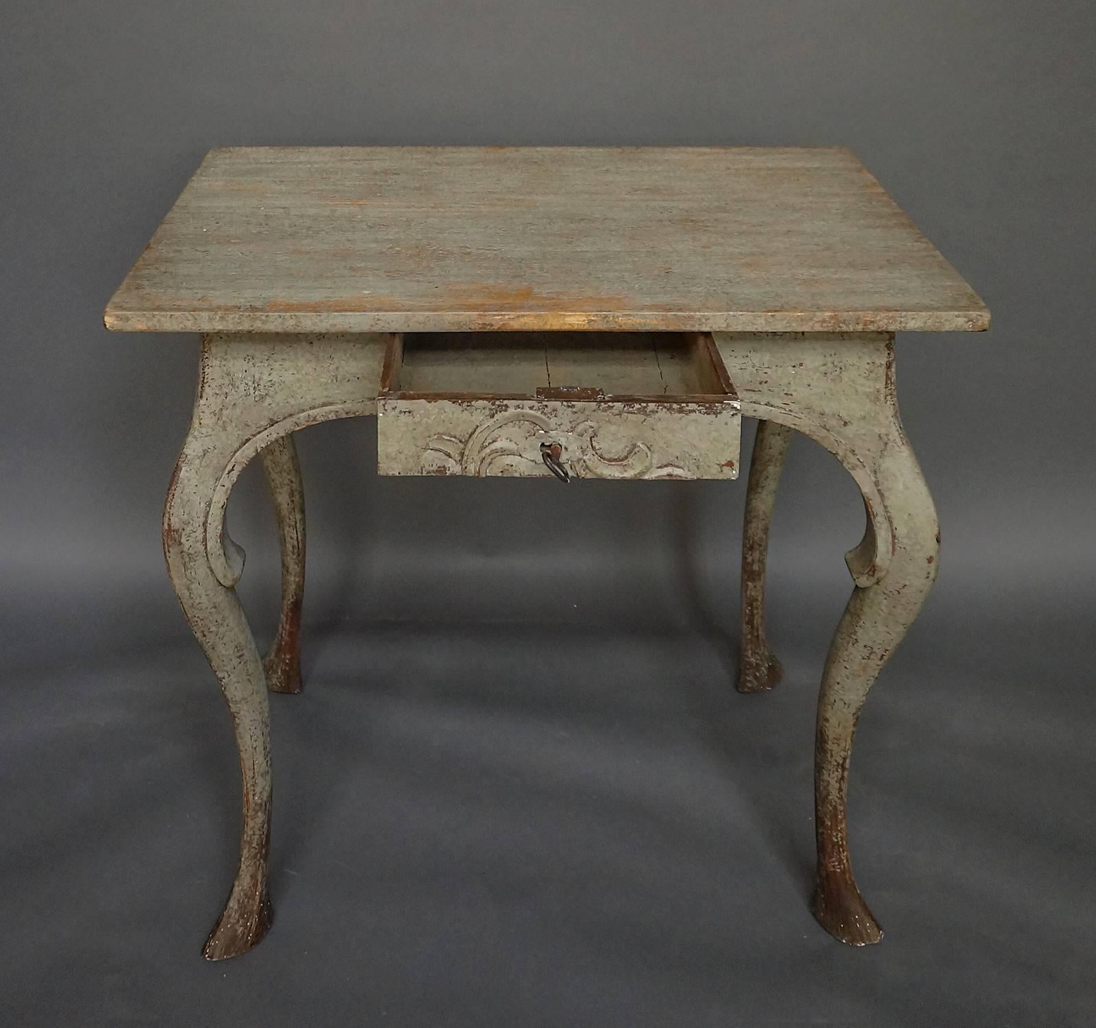 Very early Rococo side table, Sweden, circa 1700, which retains its original painted surface. Graceful carving on the front apron spans the single locking drawer. Freestanding (finished on all sides).
