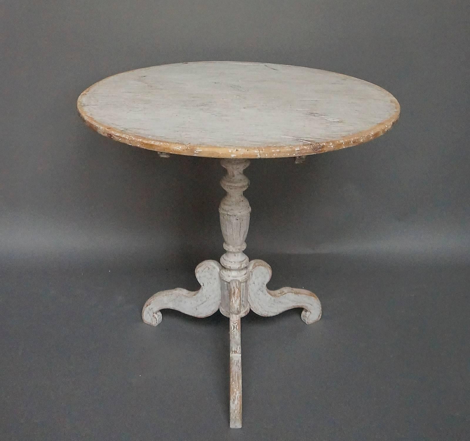 Round tilt-top table, Sweden, circa 1850, with turned pedestal base and three cyma-curved legs. Worn white paint.