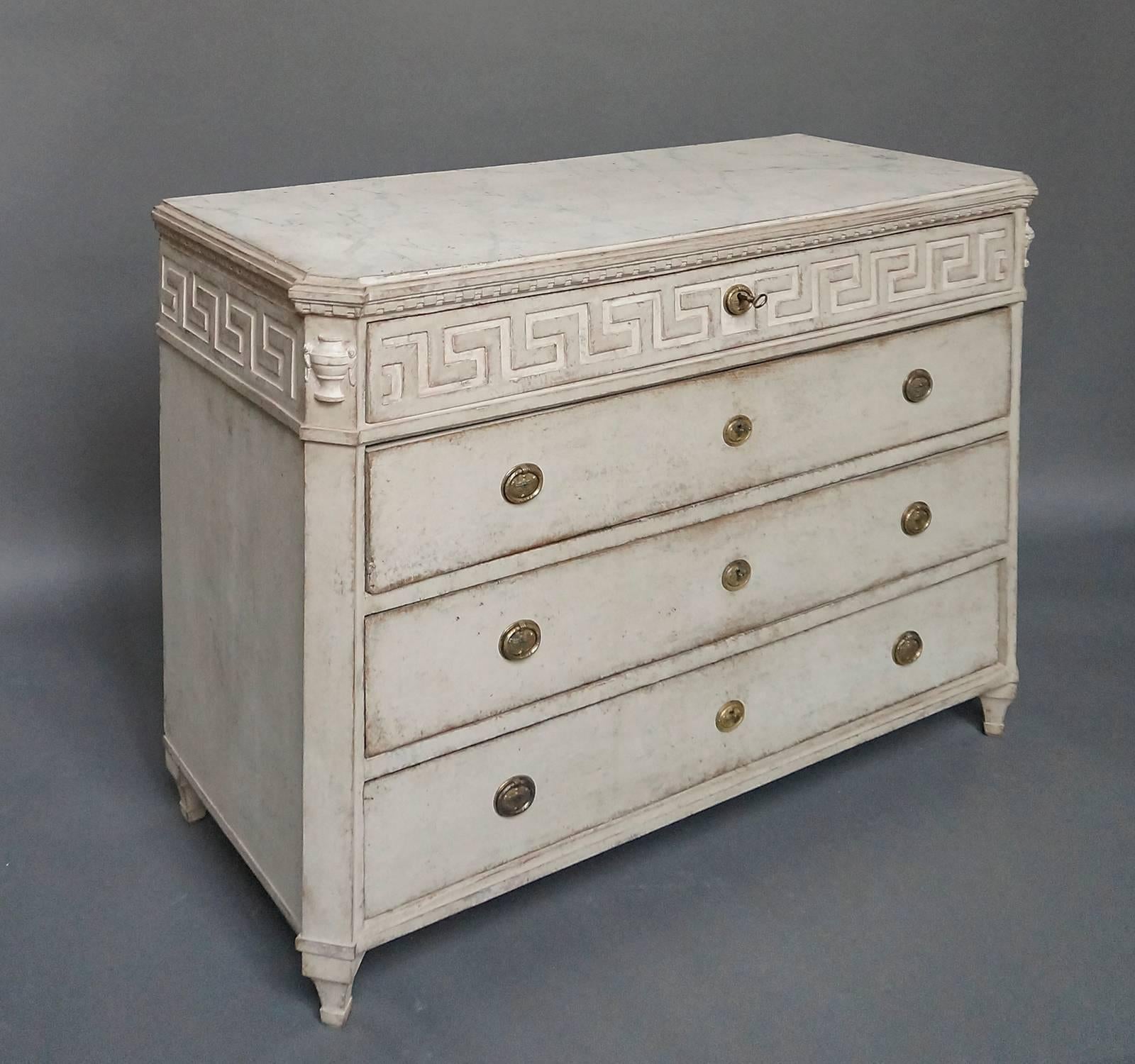 Swedish chest of drawers, circa 1860, with Greek key detail on the top drawer front and continuing around the sides. Canted corners with applied half-urns at the tops. Shaped top with painted marbling. Tapering square legs.