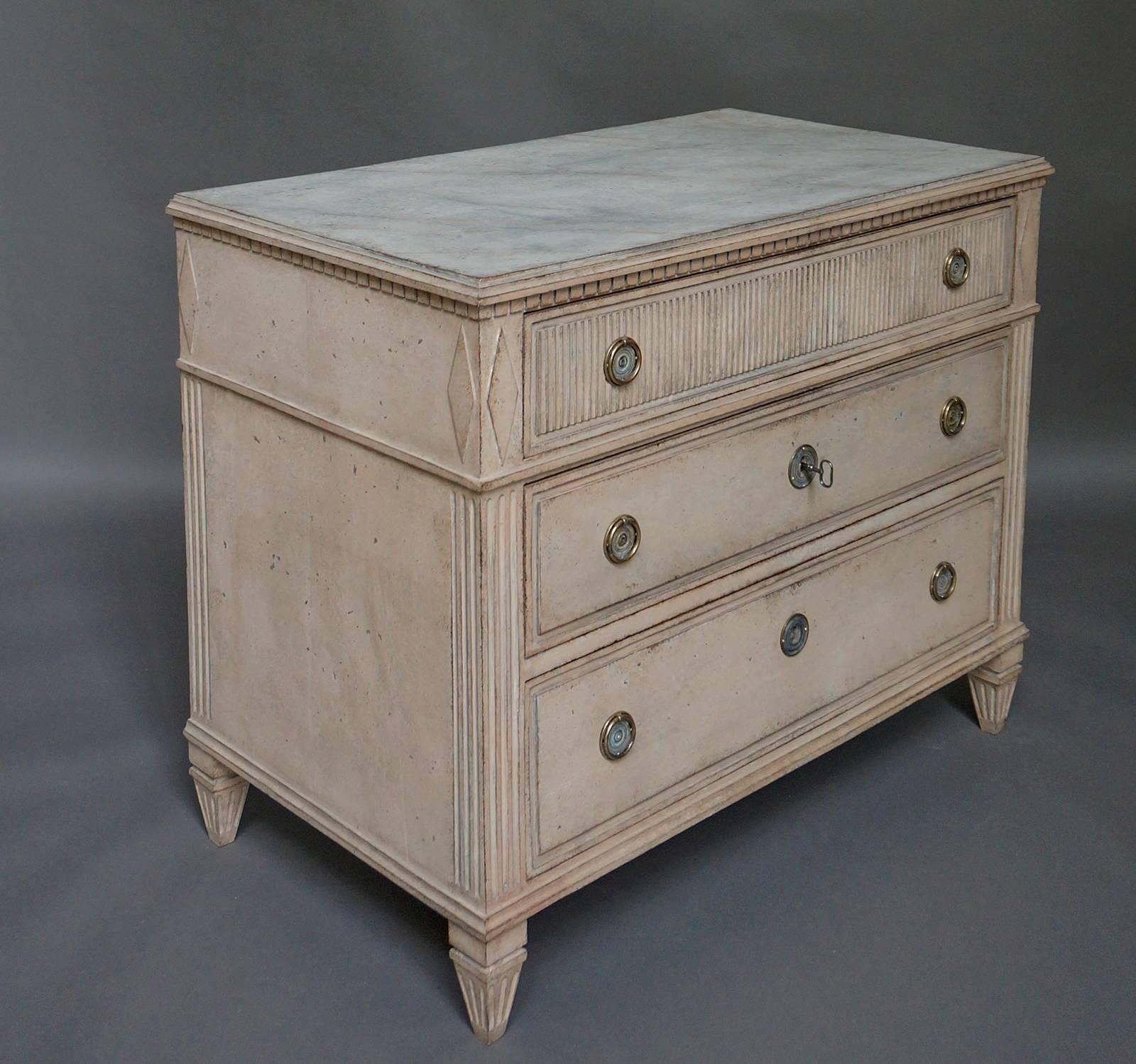 Beautifully detailed Empire chest of drawers in rich antique cream paint, Sweden circa 1880. Each upper corner on the front and sides is accented with an elongated lozenge with reeding below. Each of the three drawers has a raised panel in frame and