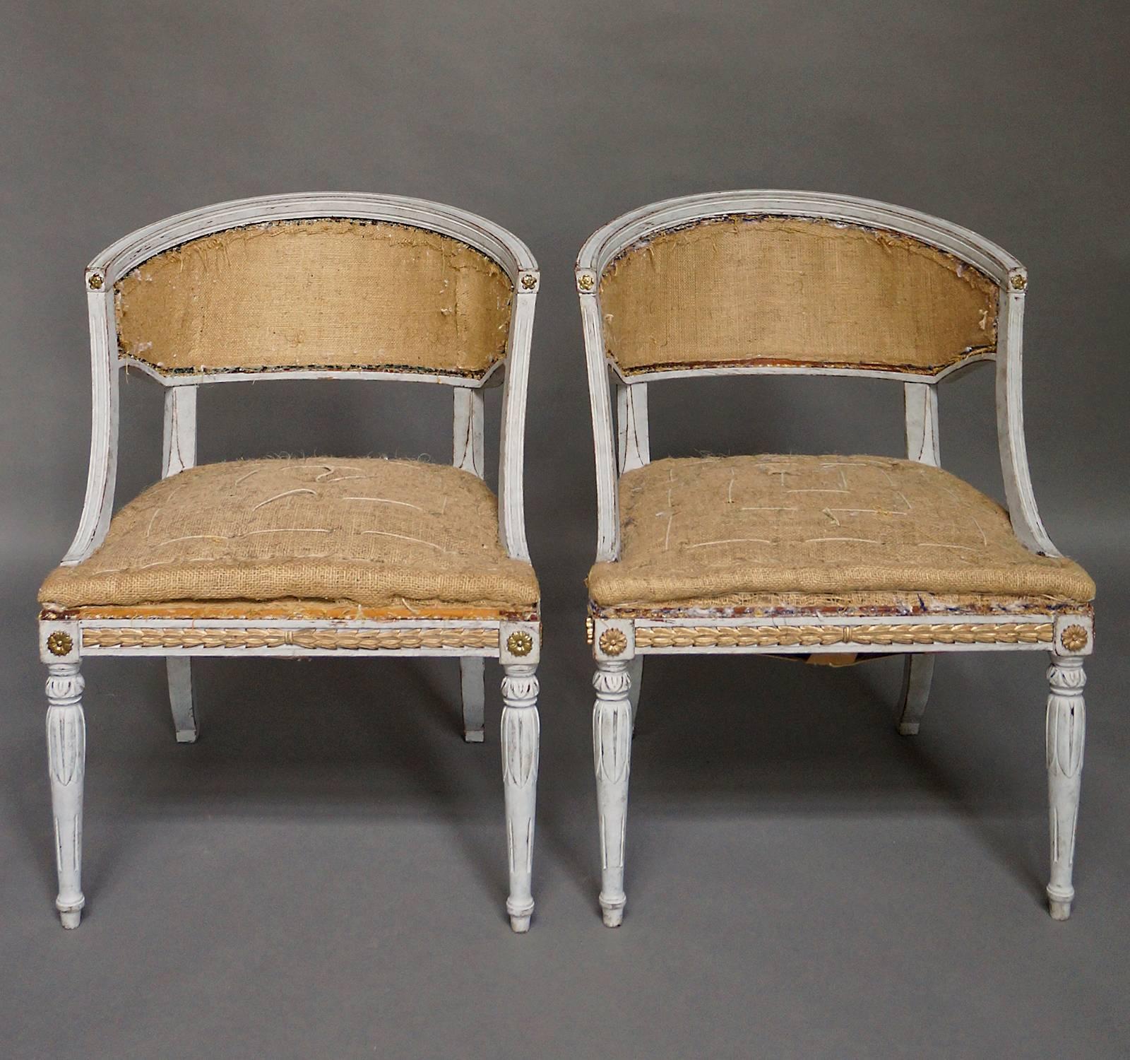 Pair of barrel back armchairs in the neoclassical style, Sweden, circa 1900. The front and side rails have inset gilded laurel leaf molding. A combination of gilt and brass rosettes mark the turnings of the arms and the corner blocks. Lotus carving