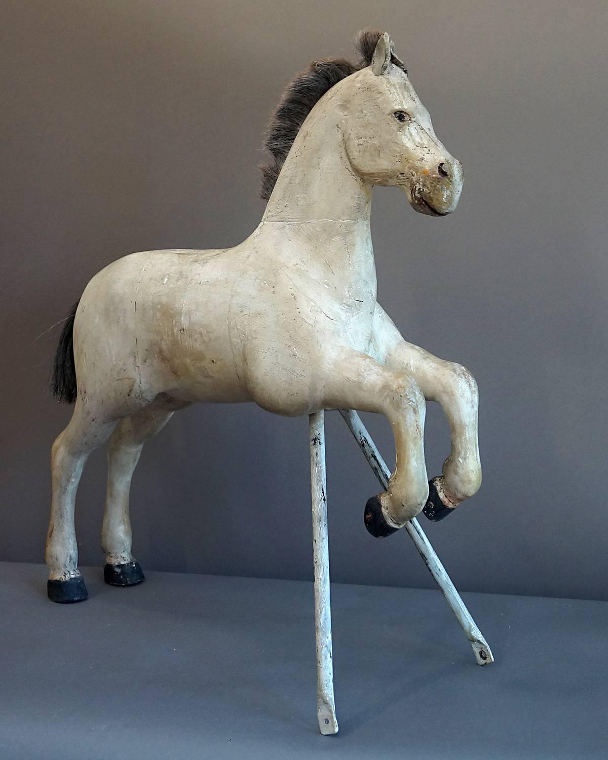 Carved Swedish horse, circa 1910, in a prancing pose and supported by a metal stand. Cropped horsehair mane and tail, leather ears, and carved feathering on the fetlocks.