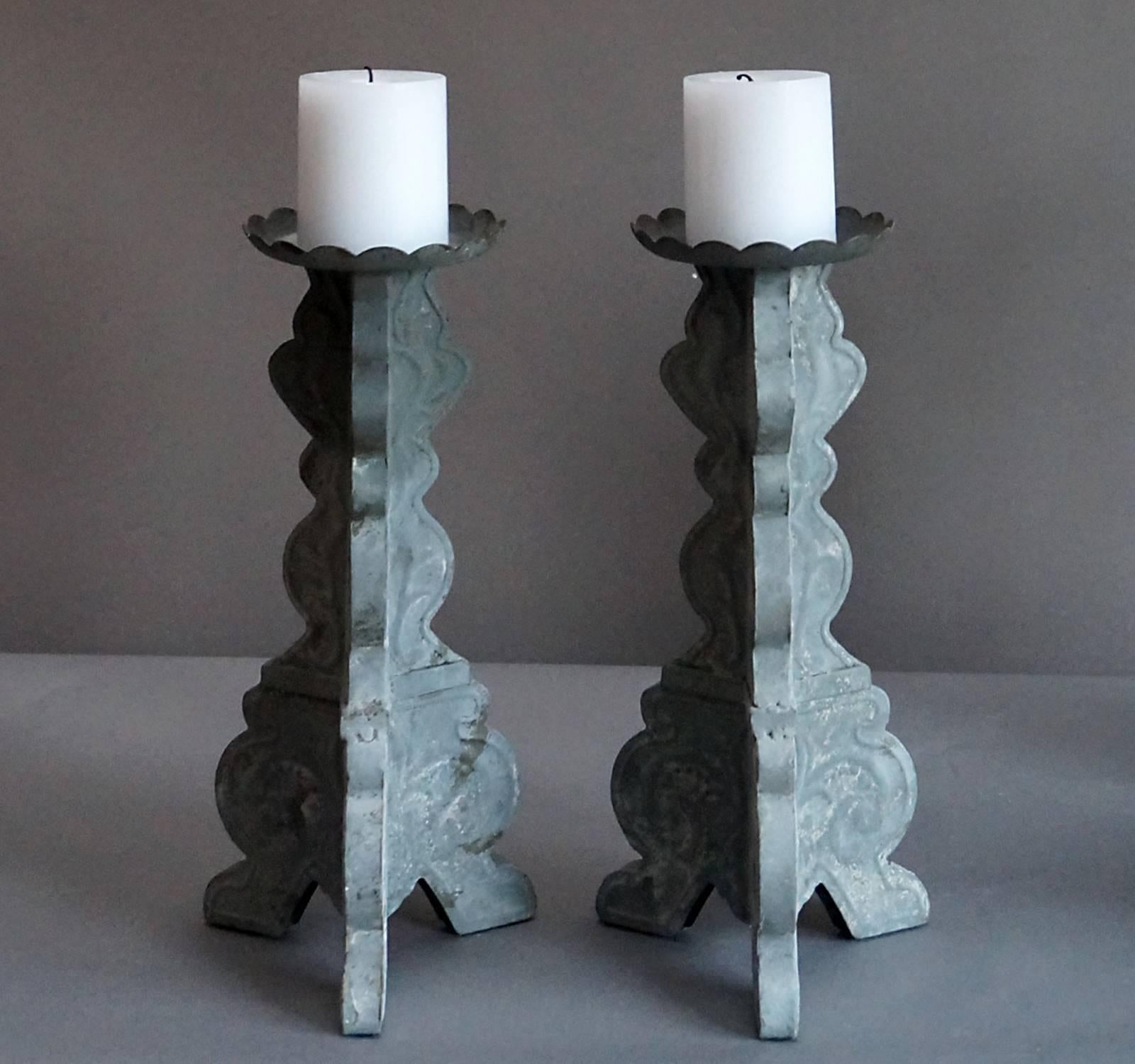 Set of four hand-hammered tin candlesticks with a Rococo feel, Sweden, circa 1850, with early grey paint. Tripod base and wide drip pan at the top.