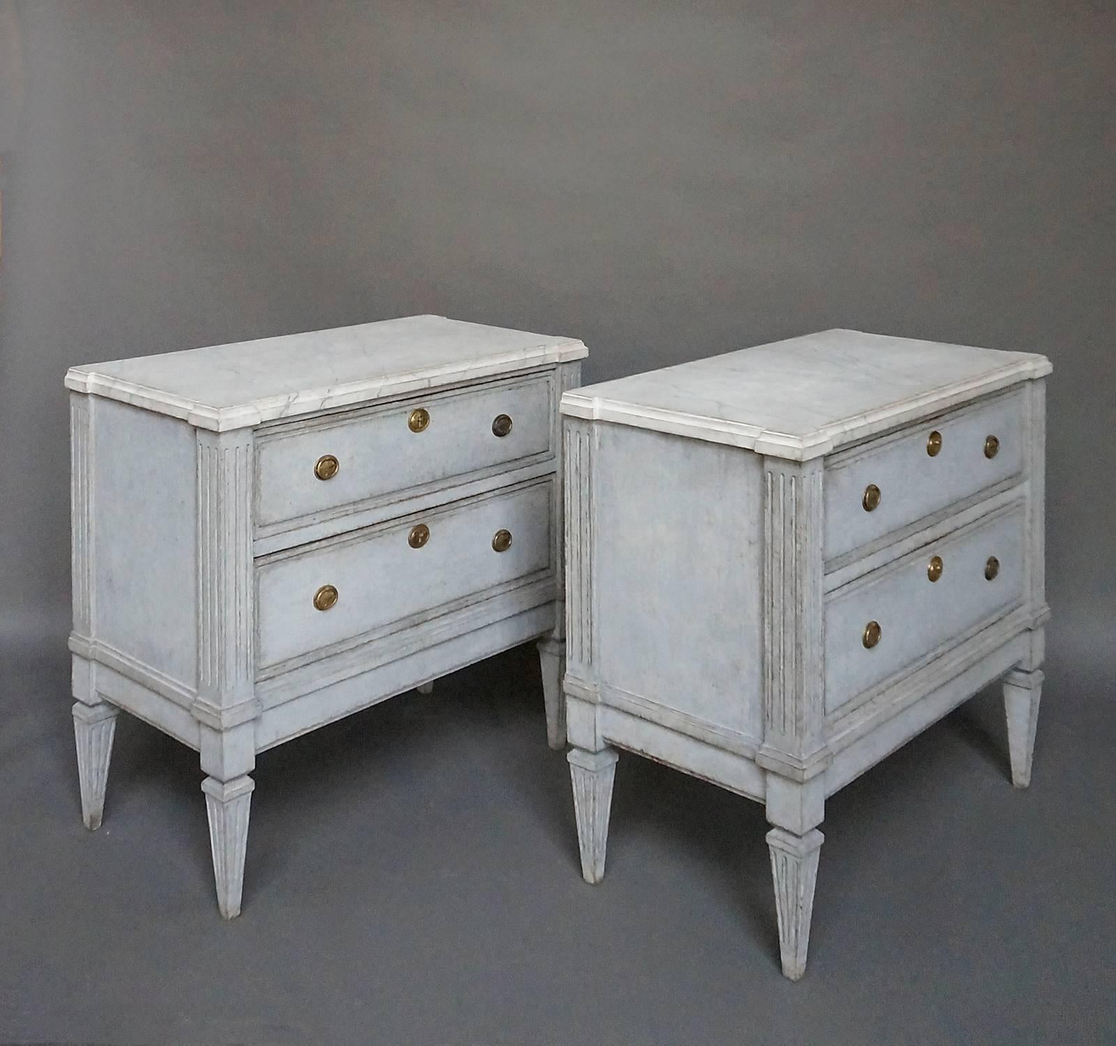 Pair of Swedish neoclassical two drawer commodes, circa 1860, with shaped tops painted with a faux marble design, reeded corner blocks, and tapering square legs. Each dovetailed drawer has raised molding around the edge and brass hardware.