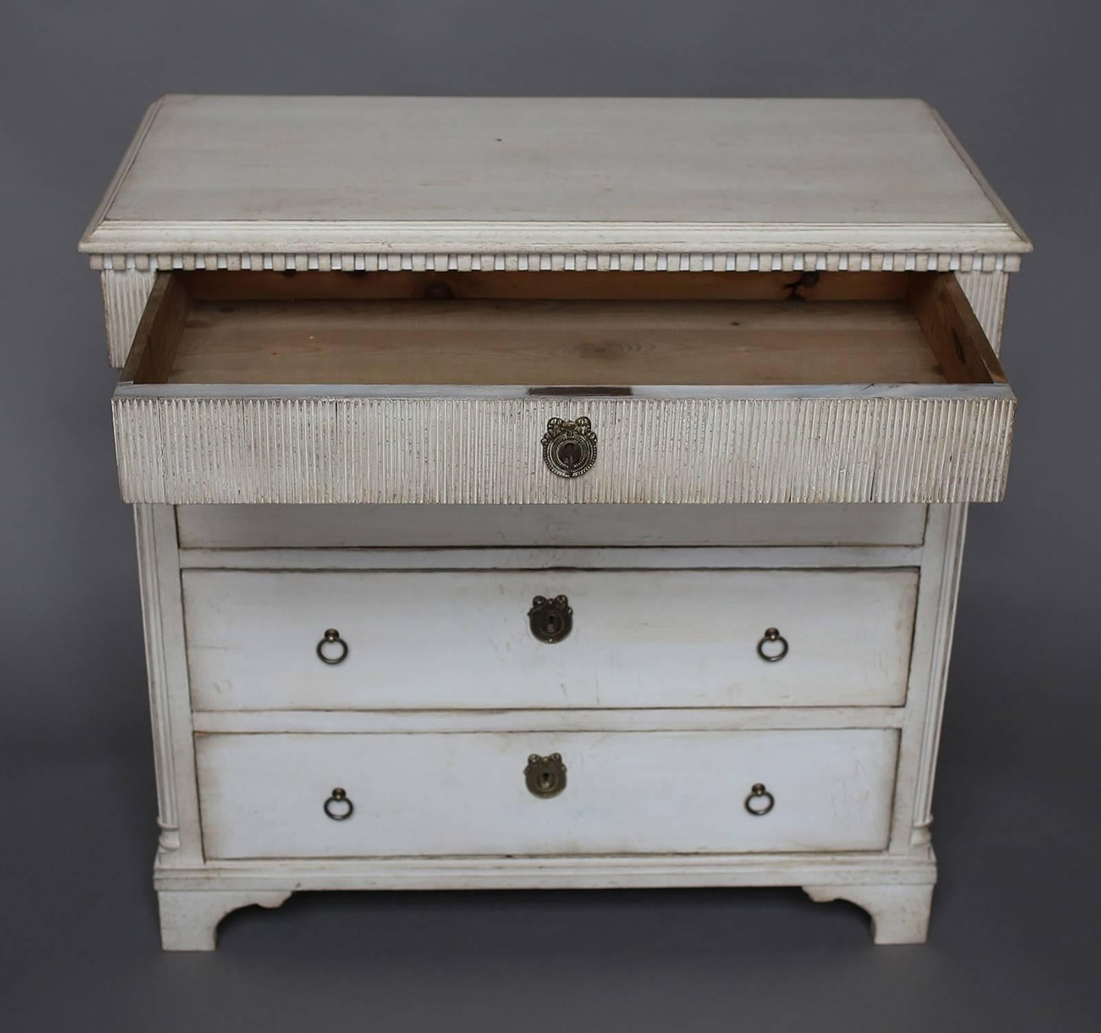 Small Louis XVI style commode, Denmark circa 1860, with four drawers. Dentil molding under the shaped top and reeding around the top drawer on three sides. Reeded quarter columns with turned detail at the front corners. Shaped bracket base.