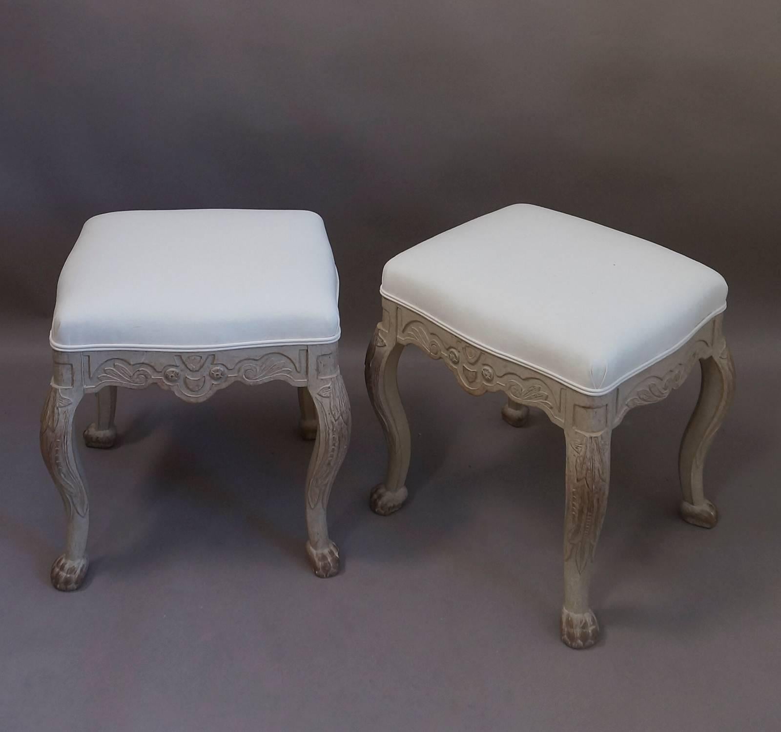 Charming pair of Rococo-style stools, Sweden, circa 1900, with carved aprons, cabriole legs with carved foliage, and lion’s paw feet, complete with claws. Upholstered seats.
