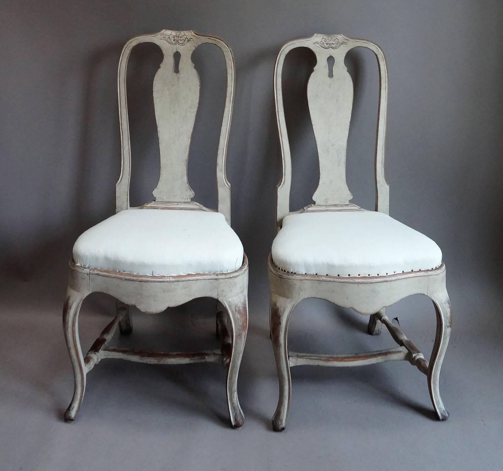 Set of four Swedish dining chairs, circa 1900, from the old Hotell Höjden in the islands east of Stockholm. Rococo style with cabriole legs, pierced splats with carved detail, slip seats and H-shaped stretchers.