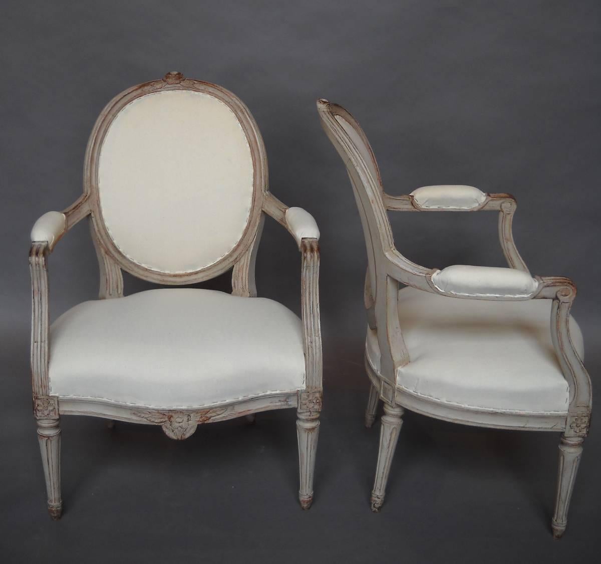 Pair of Swedish armchairs, circa 1890, in the Gustavian style. Carved rose with foliage on the crest and apron with fluted arms continuing to the carved corner blocks. Turned tapering legs. Sturdy and comfortable.