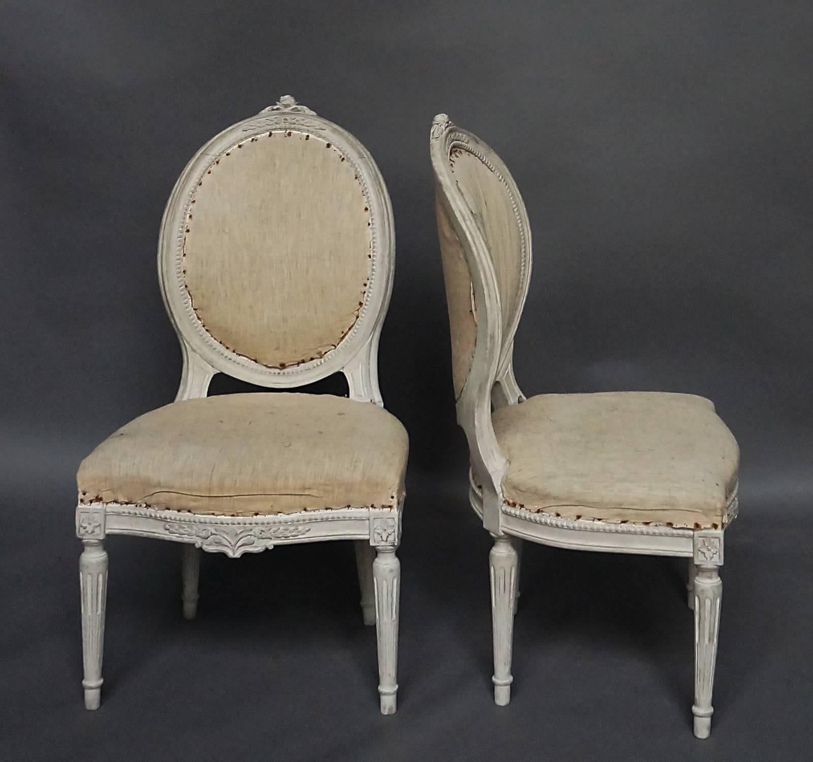 Set of four-side chairs in the Gustavian style, Sweden, circa 1900. Round, upholstered backs with carved roses at the crest. Upholstered seats with carved apron and tapering, round legs.