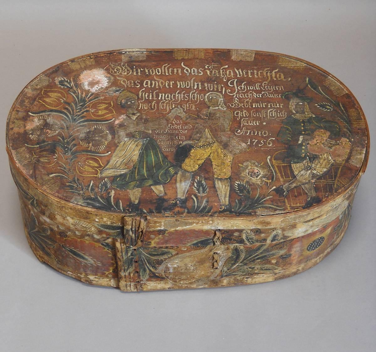 Beautifully painted German bride’s box dated 1756. On the top are pictured two dancers described as “Gredel and Hans make a Bavarian dance,” and a musician with a zither. The couple say, “We want to dance. That way, we can still be close at night.”