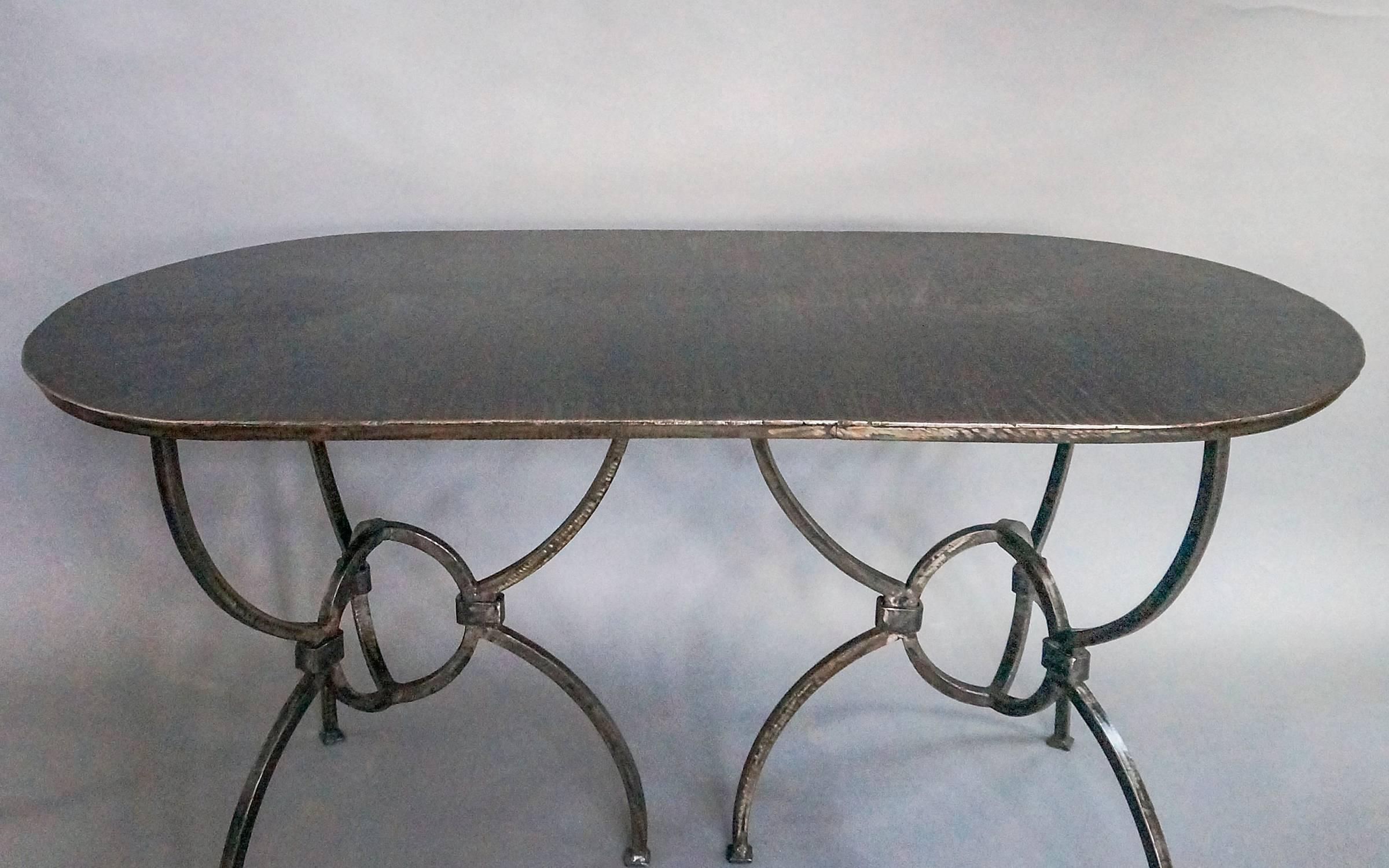 Oval Sundial dining table handmade with a reclaimed steel top. Geometric arc and strap base with padded feet.