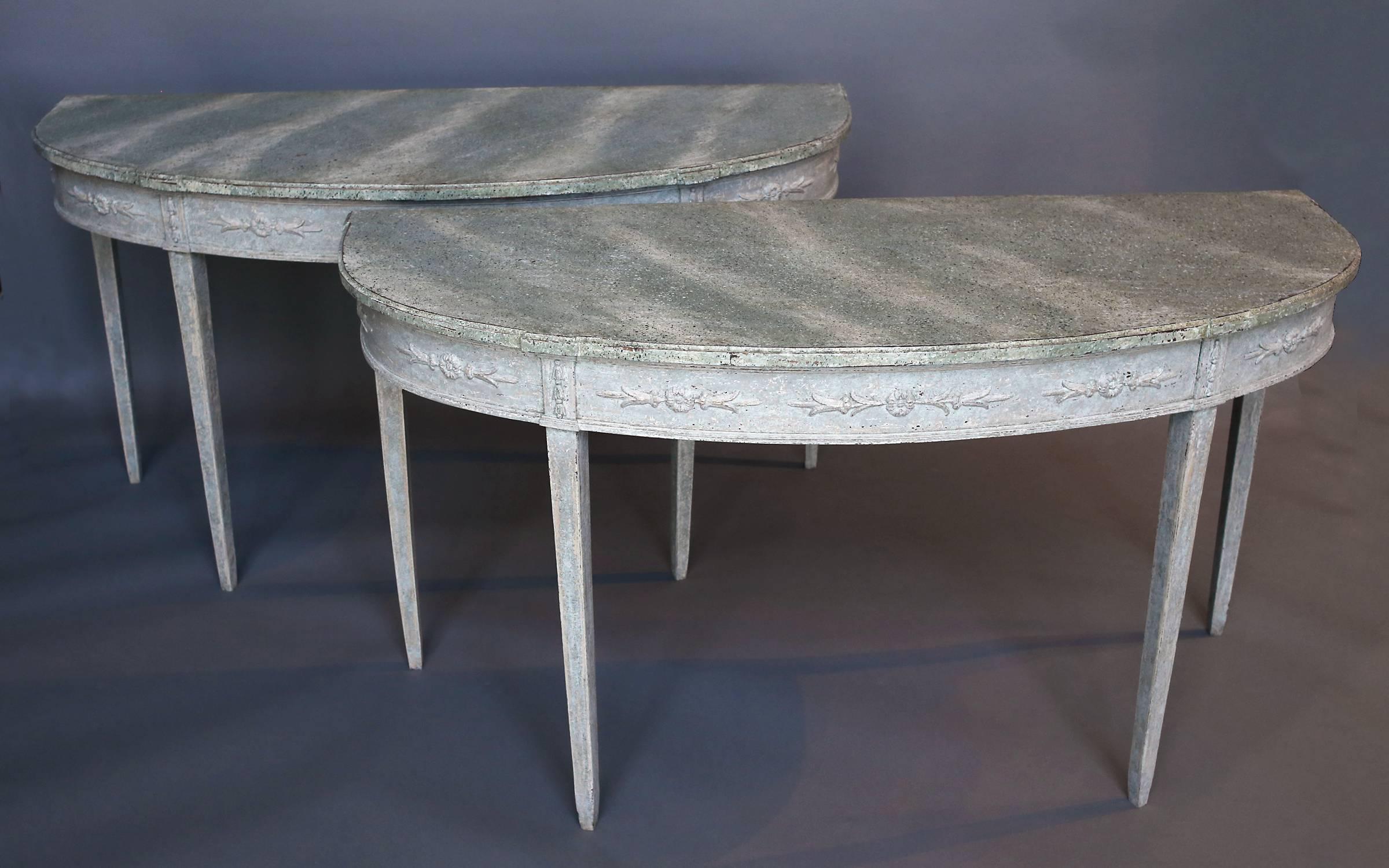 Rare pair of period Gustavian console tables, Sweden, circa 1780, with marbleized tops. Wide aprons are decorated with applied floral carvings above simple, tapering legs. Original paint, including the marbleized tops.