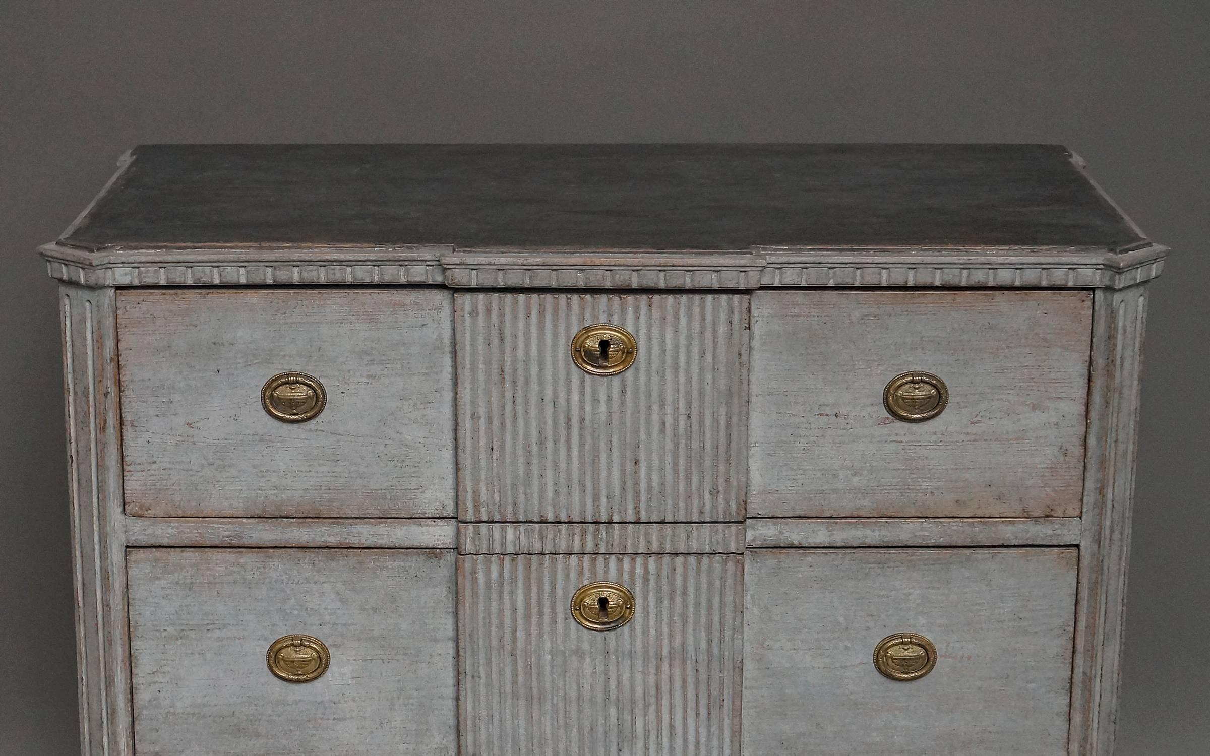 Swedish chest of drawers, circa 1870, in the Gustavian style and having three drawers with reeded panels, canted corners and dentil molding under the shaped top. The worn gray paint has a beautiful patina and contrasts well with the darker painted