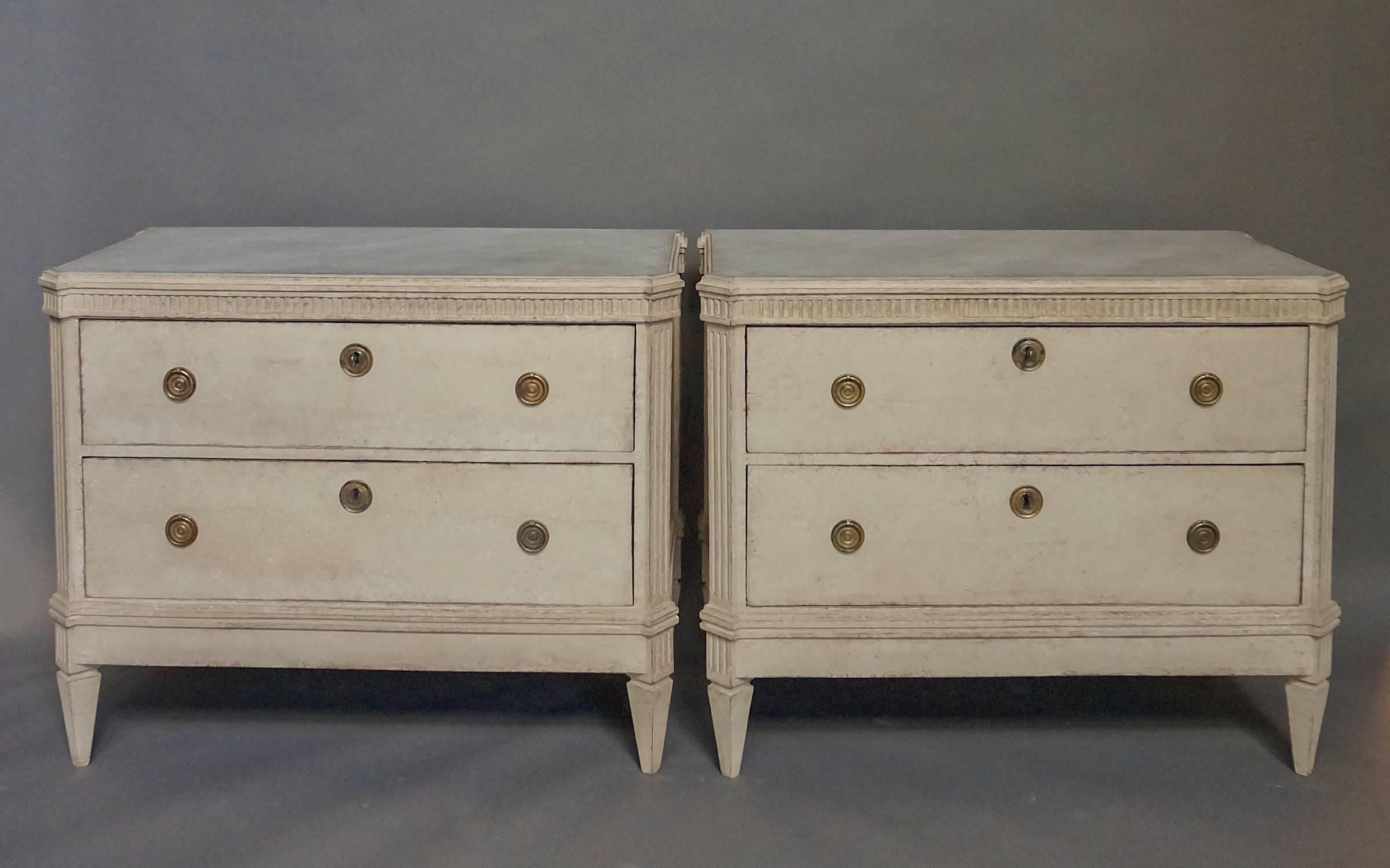 Pair of Swedish commodes, circa 1860 with faux marble tops. Dentil molding runs around the front and sides above the canted corners with reeded corner posts and the two deep drawers. Tapering square legs.