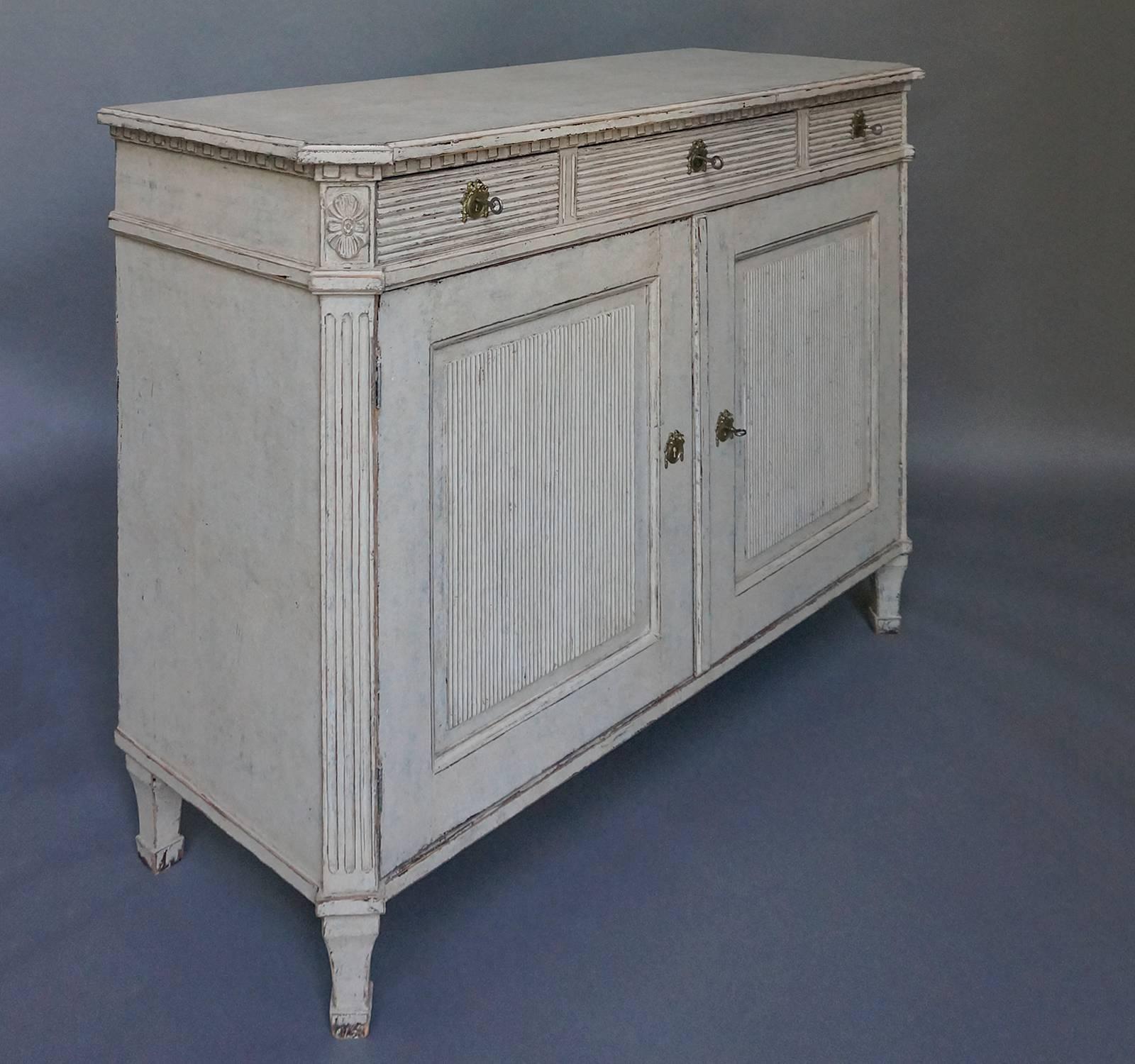 Swedish sideboard in the Gustavian Style, circa 1860, with three drawers over two doors, all of which feature reeding. Shaped top and canted corners. Two interior shelves.