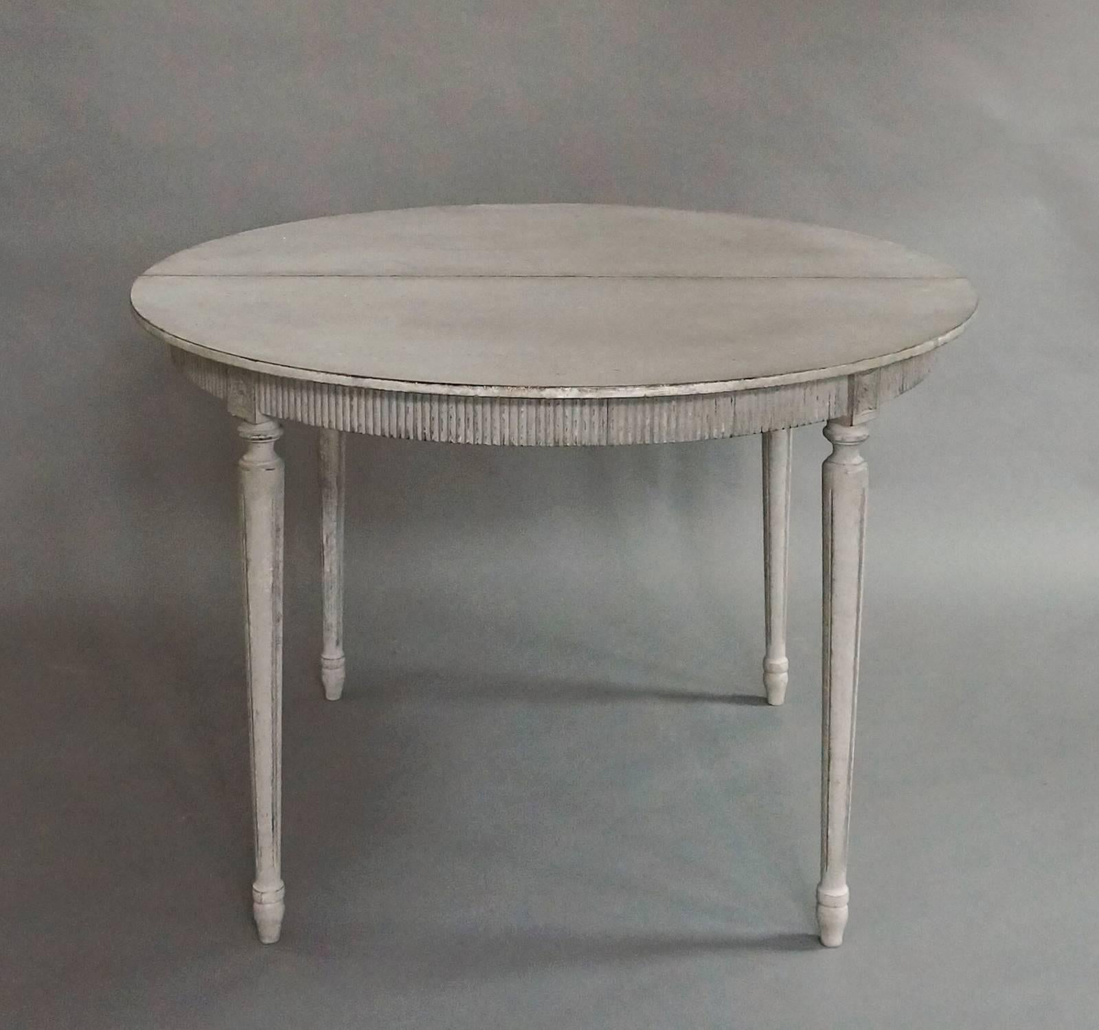 Swedish dining table in the Gustavian style, circa 1890. Fluted apron with quatrefoil detail at the top of each turned leg. Two 19