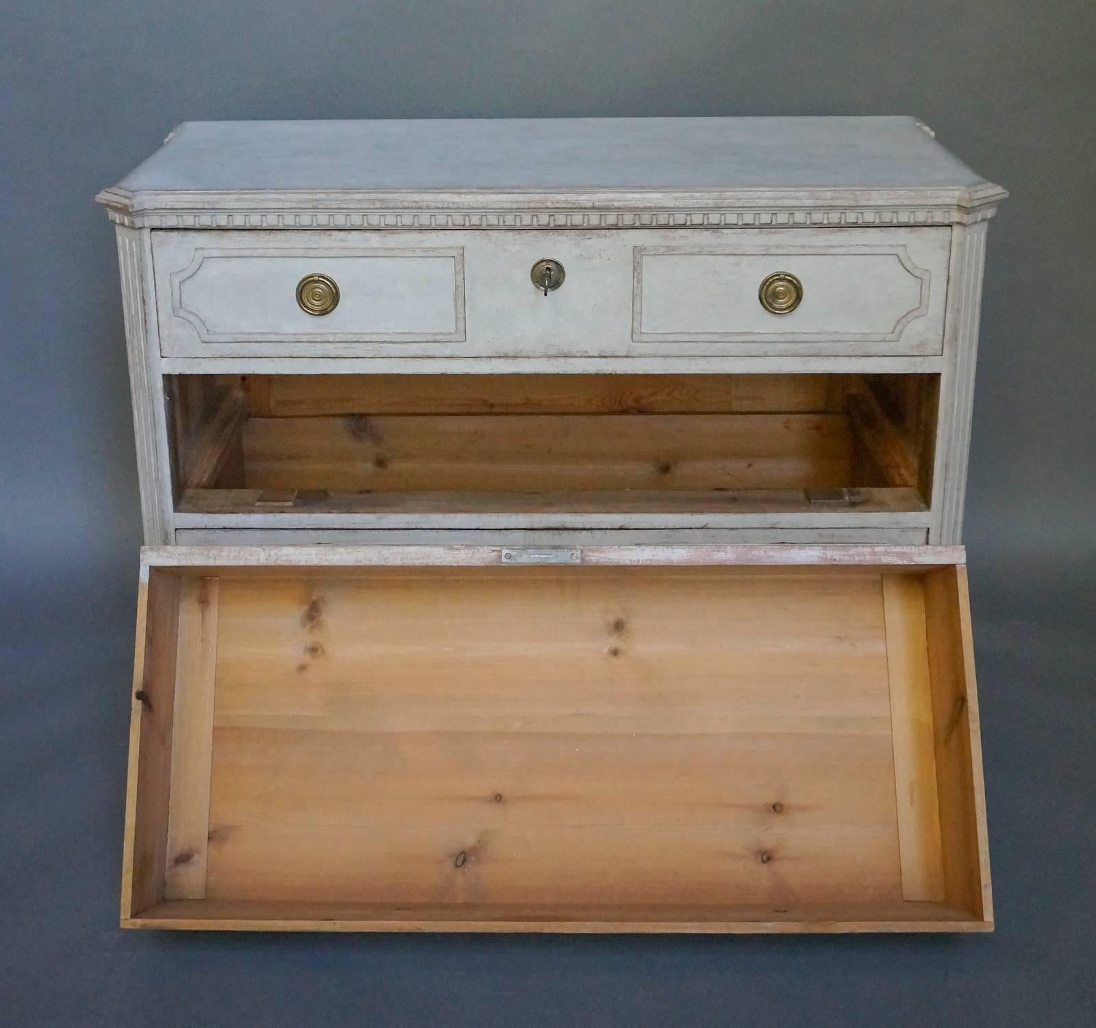 Chest of drawers, Sweden circa 1880, in the Gustavian Style. Shaped top with canted corners and dentil molding. Each of the three drawers has two panels defined by incised borders, and brass pulls and escutcheons. Tapering square legs. Classic