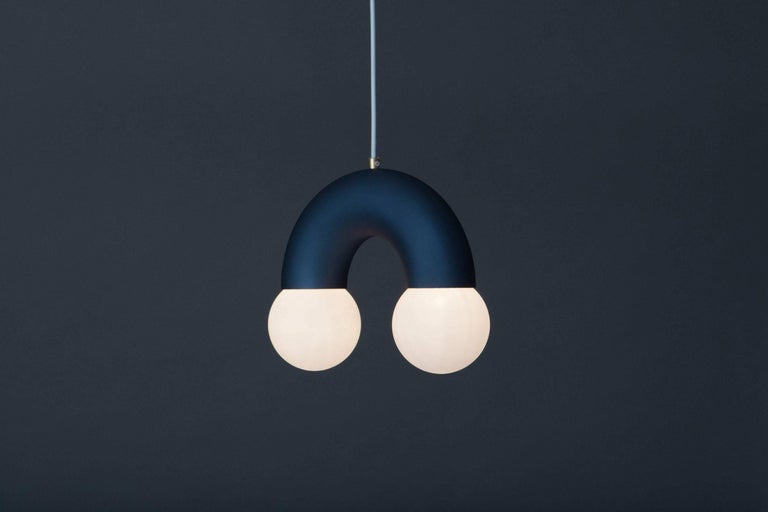 Anodised sandblasted and bent aluminium tube as the main structure with 10cm ø glass globes. The colour of lamp is available in steel blue and gold and natural steel. Brass fixture for holding the textile cable.