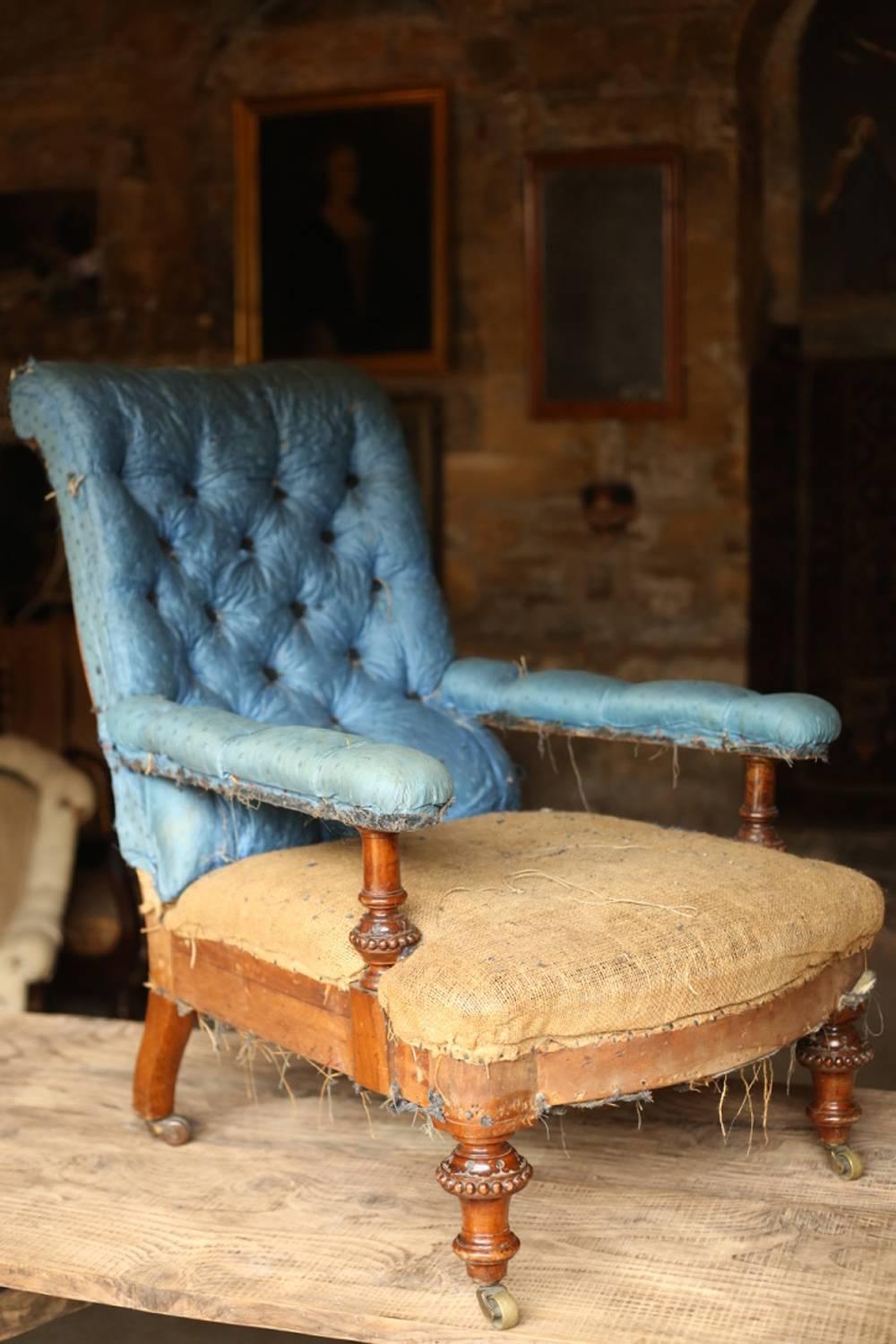 This is a very stylish last 19th century, low deep English country house armchair with a buttoned back. Retains part of its original blue silk upholstery that is very vivid even after all these years. High quality caved front legs with original