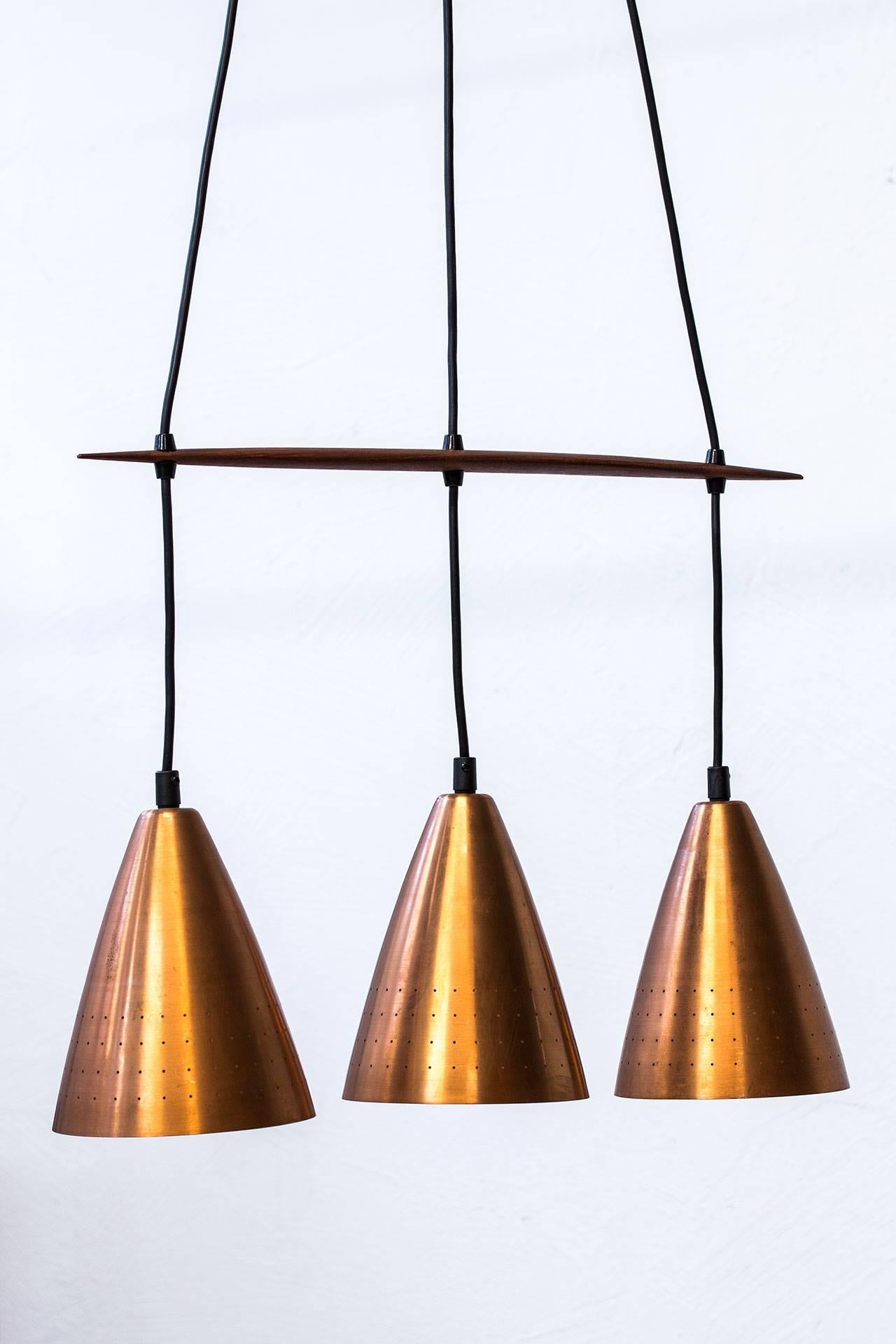 Ceiling lamp in copper and teak designed by Hans-Agne Jakobsson, in Åhus, Sweden. Model from the early 1950s with three perforated copper shades. Copper ceiling cup.
Stretcher in teak. Adjustable height and length for the shades. New electricity.