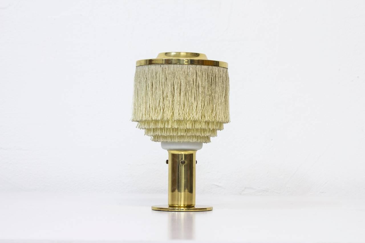 B 145 silk fringes table lamp
by Hans – Agne Jakobsson.
Made by his own company at
Markaryd in Sweden during
the 1960s. Brass light fixture
with attached creamy white
silk fringes. White opaline
glass diffuser inside.