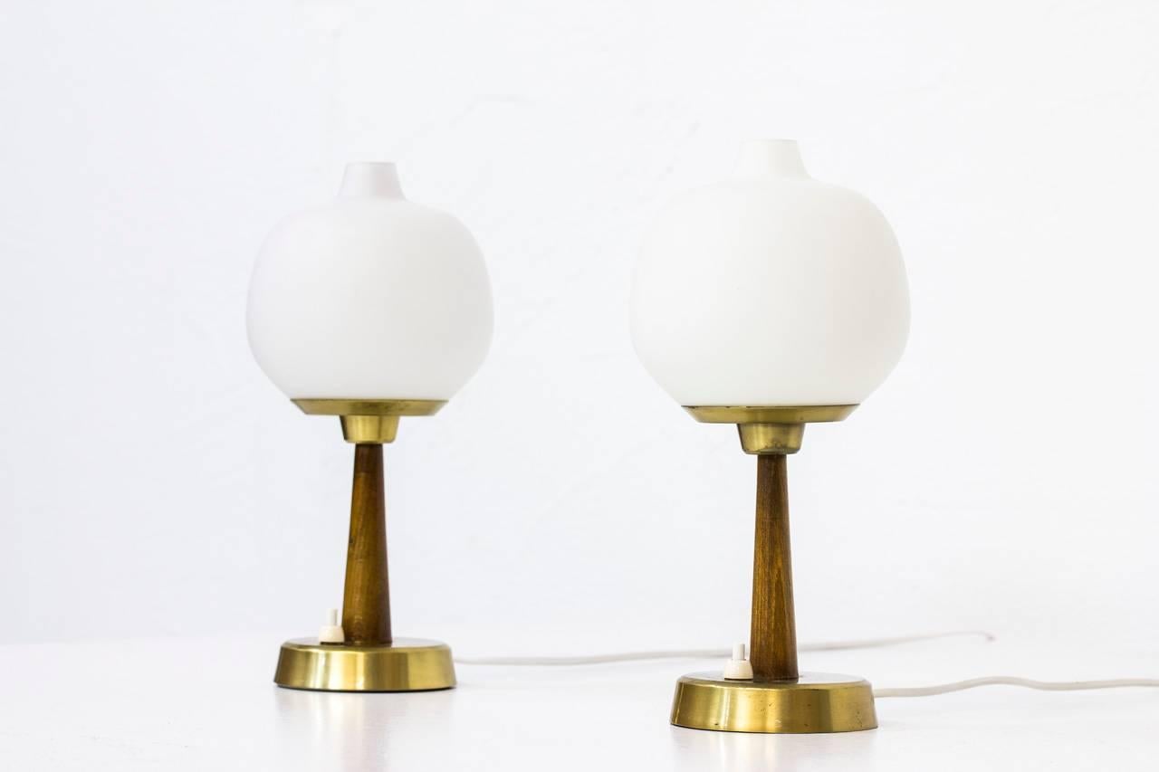 Pair of table lamps model 702 designed by Hans Bergström. Produced by his own company Ateljé Lyktan in Åhus, Sweden in the 1950s. Stained beech stem with brass base and support. Opaline glass shade. Light switch on the base.