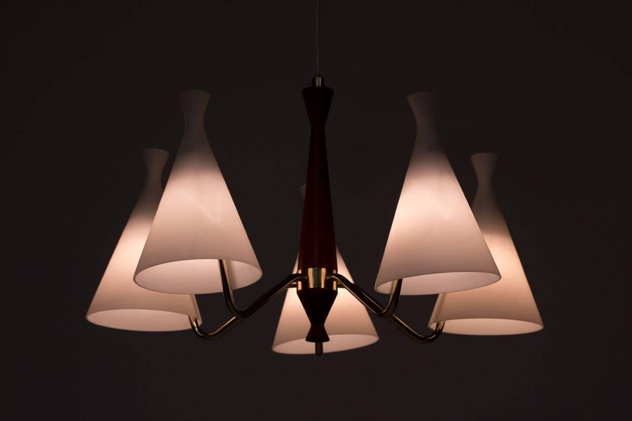 Five-armed chandelier designed by Svend Aage Holm Sørensen for Swedish manufacturer ASEA during the 1950s. Teak stem, polished brass arms and ceiling fitting. Diffusers in opaline glass.