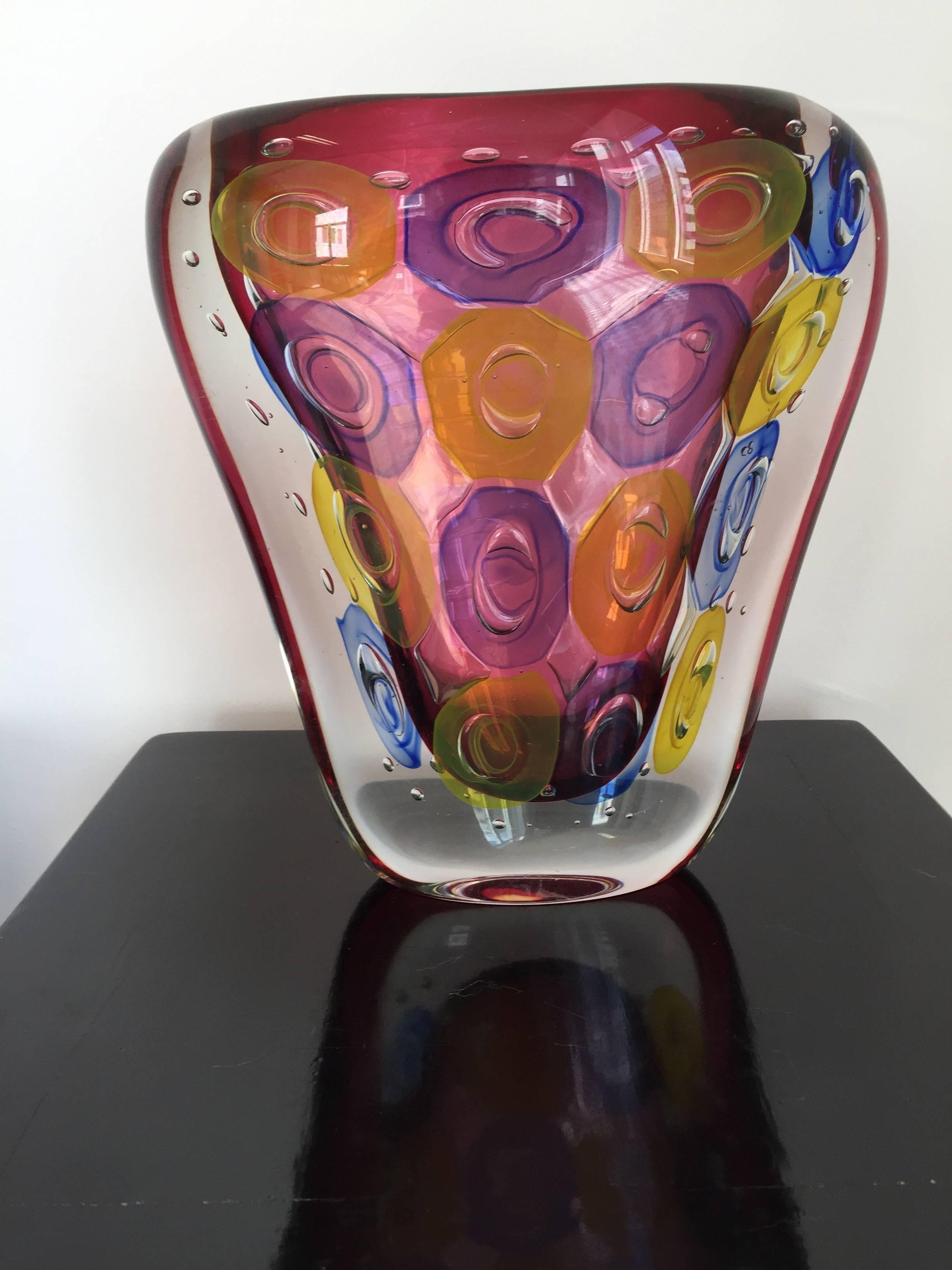 Anelly vase, crystal by Luigi Onesto Sommerso technique, oval shape, size 29 H x 25 W x 9 D cm,
signed on the bottom L. Onesto Murano, the main color is a light vine red with yellow and blue ornaments.