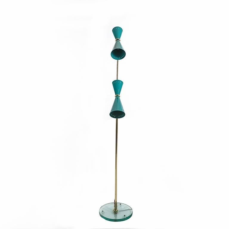 Truly outstanding Italian, midcentury, two armed floor lamp with each tubular brass arm embellished at the bottom with a brass acanthus motif and standing on a thick glass base. This base is slightly elevated off the floor resting on 3 pads. The