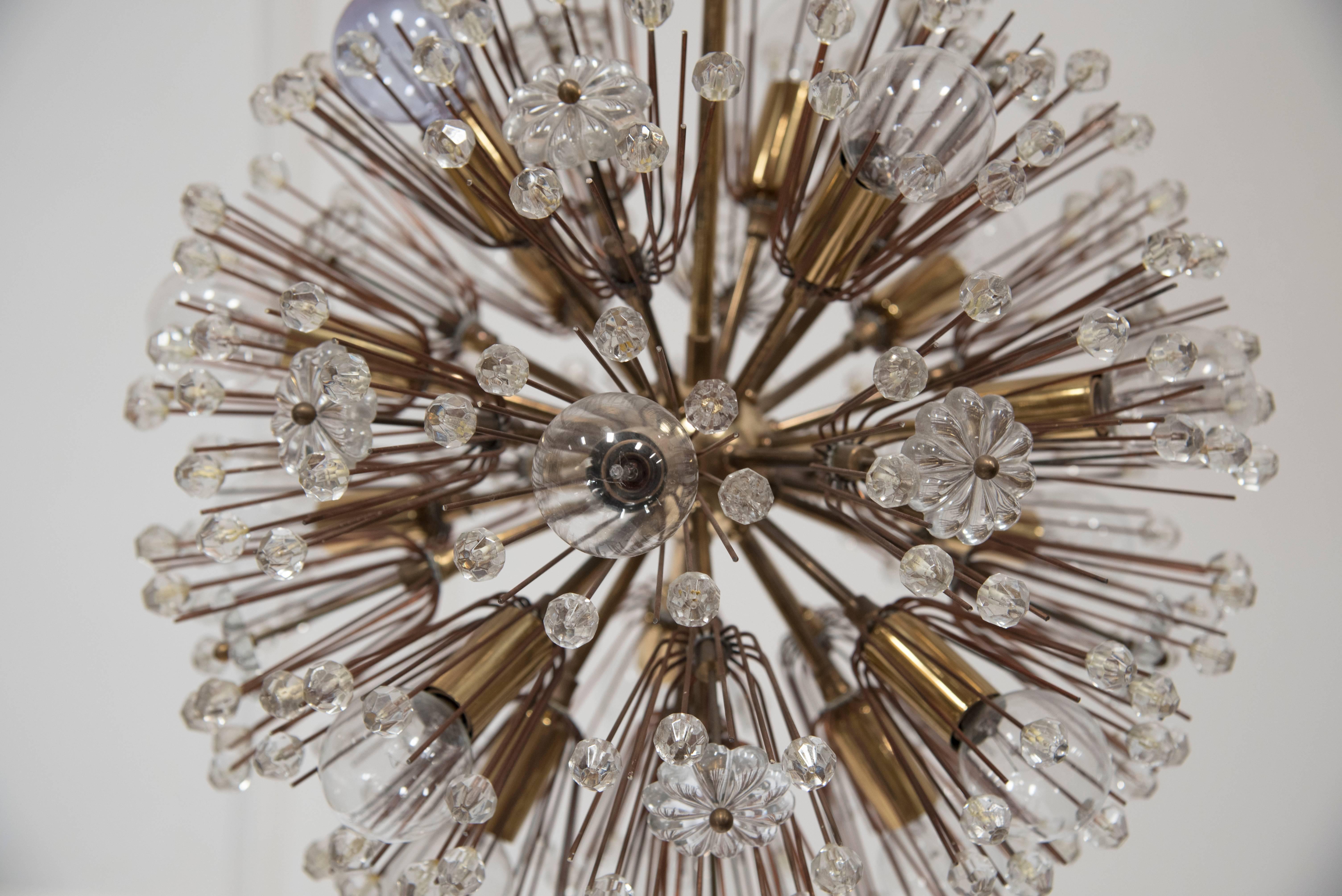 A radiating Austrian crystal starburst form eighteen-light chandelier. The circular forms emanate from brass adorned with faceted crystal beads and stars achieving an explosion of light. J L Lobmeyer designed the chandelier for the Metropolitan