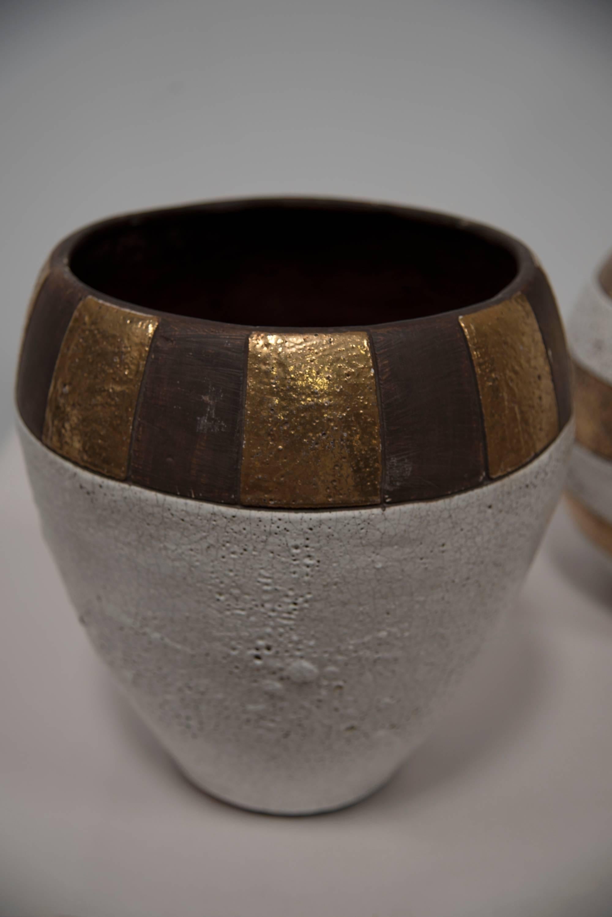 A robust set of three American beige, black striped and natural coloured glazed pottery vessels with gilt gold highlights and crackling glaze. Engraved as JARU designs. Jaru Pottery was founded in 1958 but is no longer available on the marketplace.
