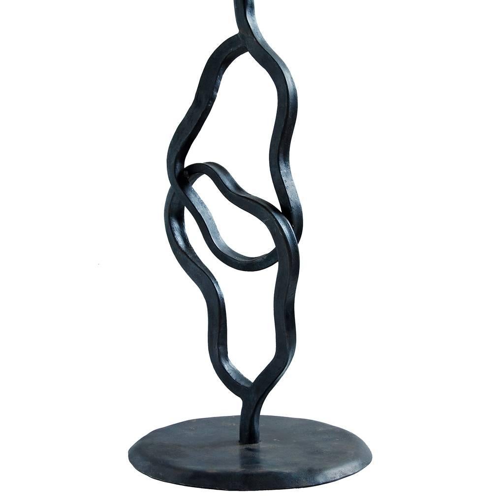 A handmade wrought iron, contemporary table lamp.

With its unconventionally formed, interlocking loops, this abstract collusion of two shapes provides a sculptural piece that makes a statement, yet allows this piece to be interpreted in the eye