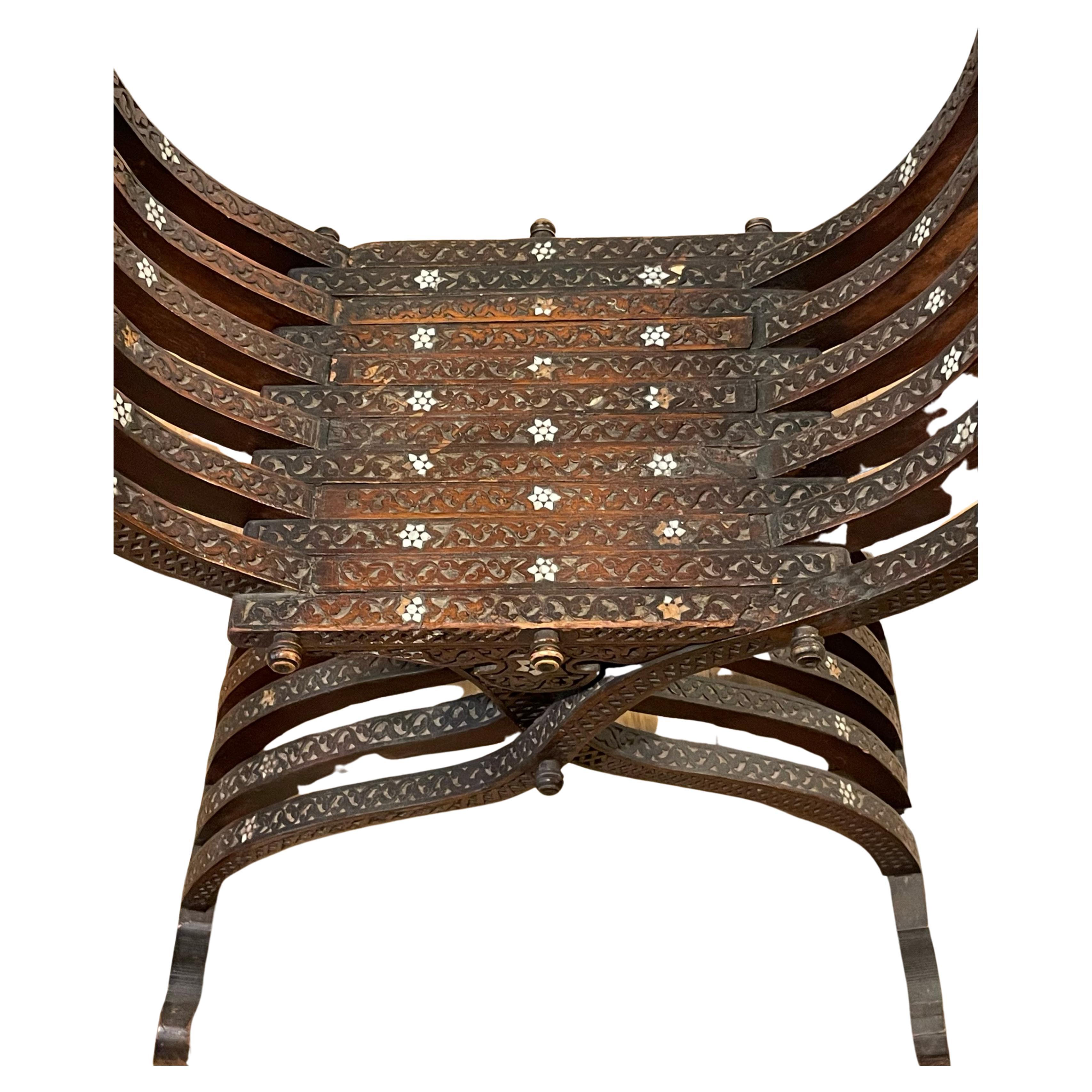 Banc Savonarola X sculpté et marqueté. Fabriqué dans le style renaissance avec des détails floraux sculptés, le banc est circa 1900, fabriqué en Inde pour l'exportation vers l'Europe.  