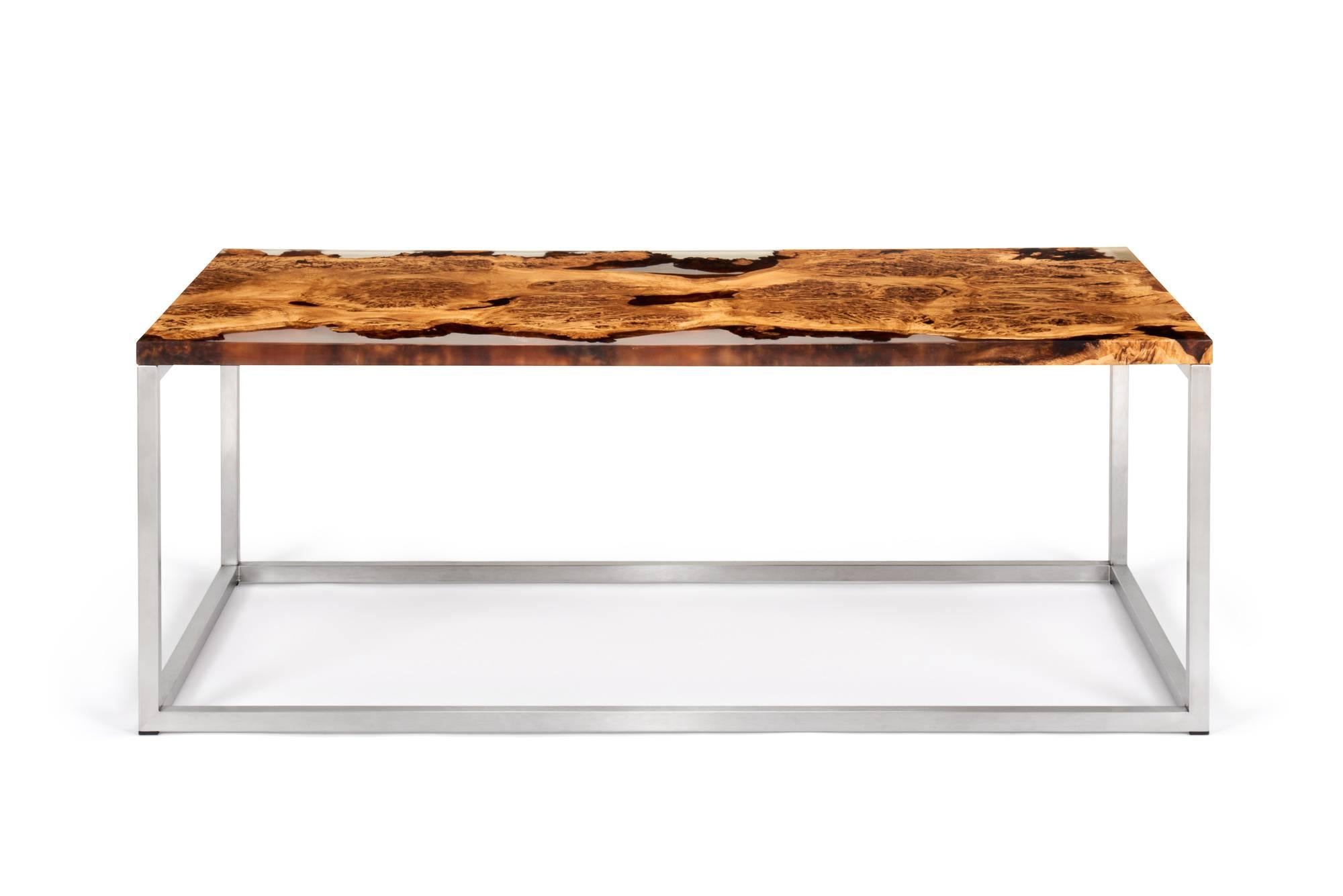 This unique coffee table is made from English oak burr. The wood has been cast in a clear resin allowing for a beautiful view of the live edges and grain pattern. The rectangular base selected for this table is brushed stainless steel.