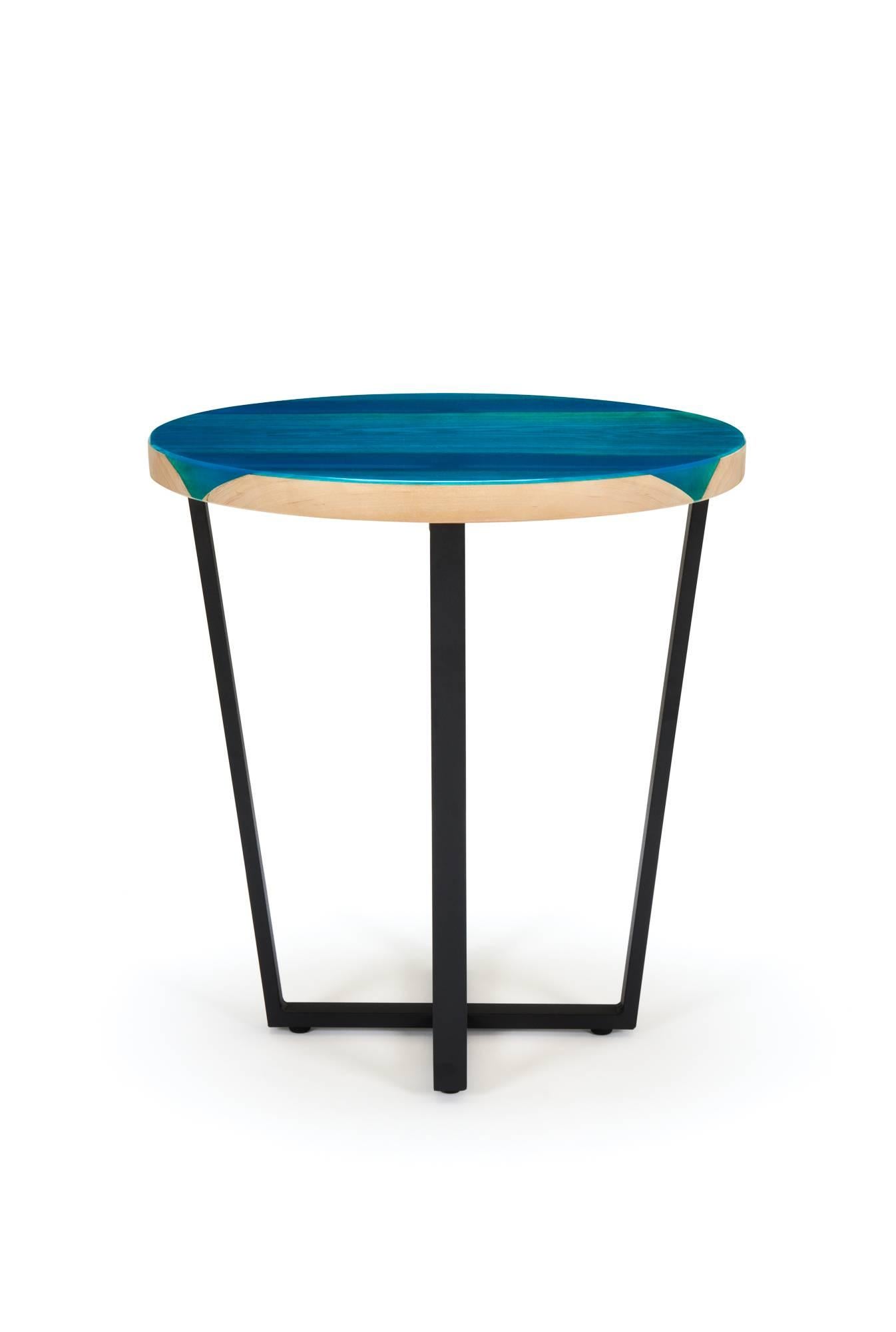This round side table features English Ash encased and glazed with blue resin. The high gloss resin across the top of the ash brings the grain to life, while at the same time contrasts perfectly with the light colored end grain. The black powder