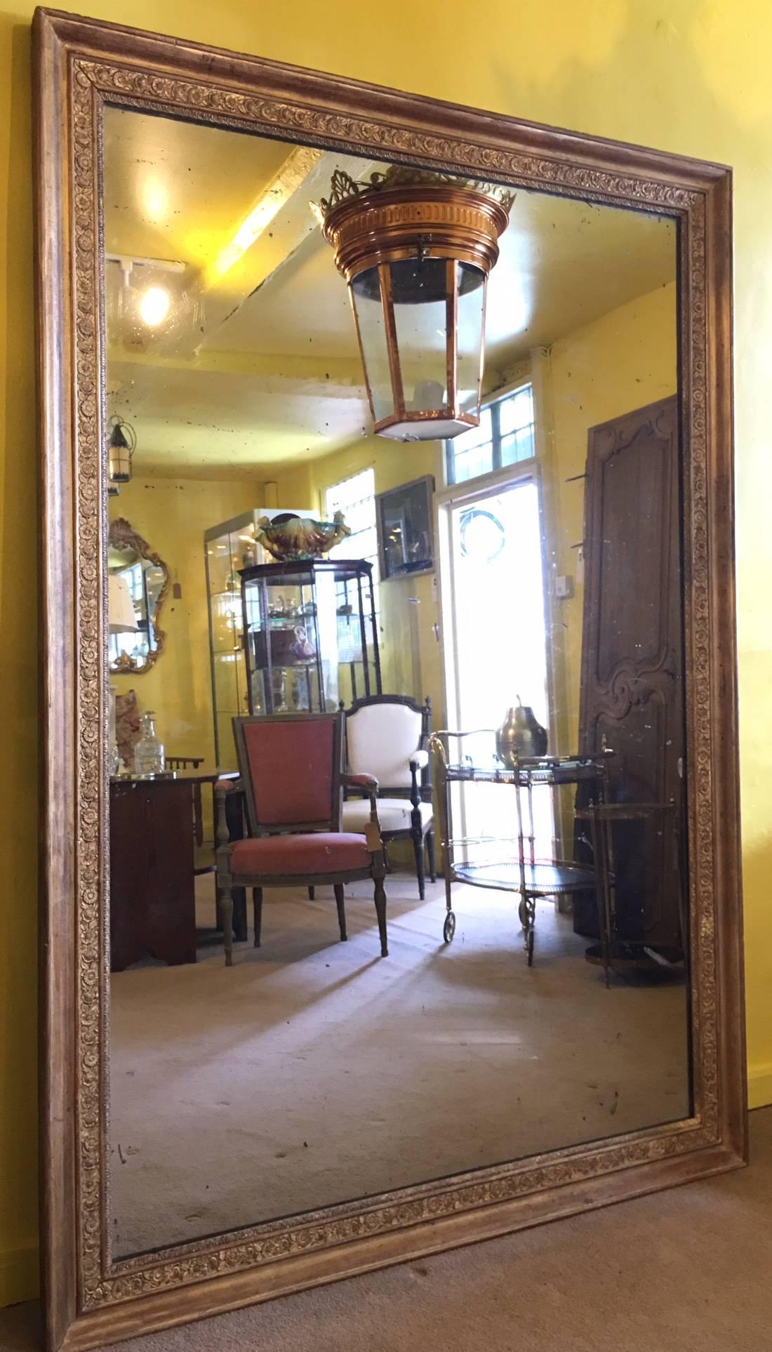 A large late 19th century French giltwood and gesso mirror with original glass, the frame decorated with flowers and foliage.