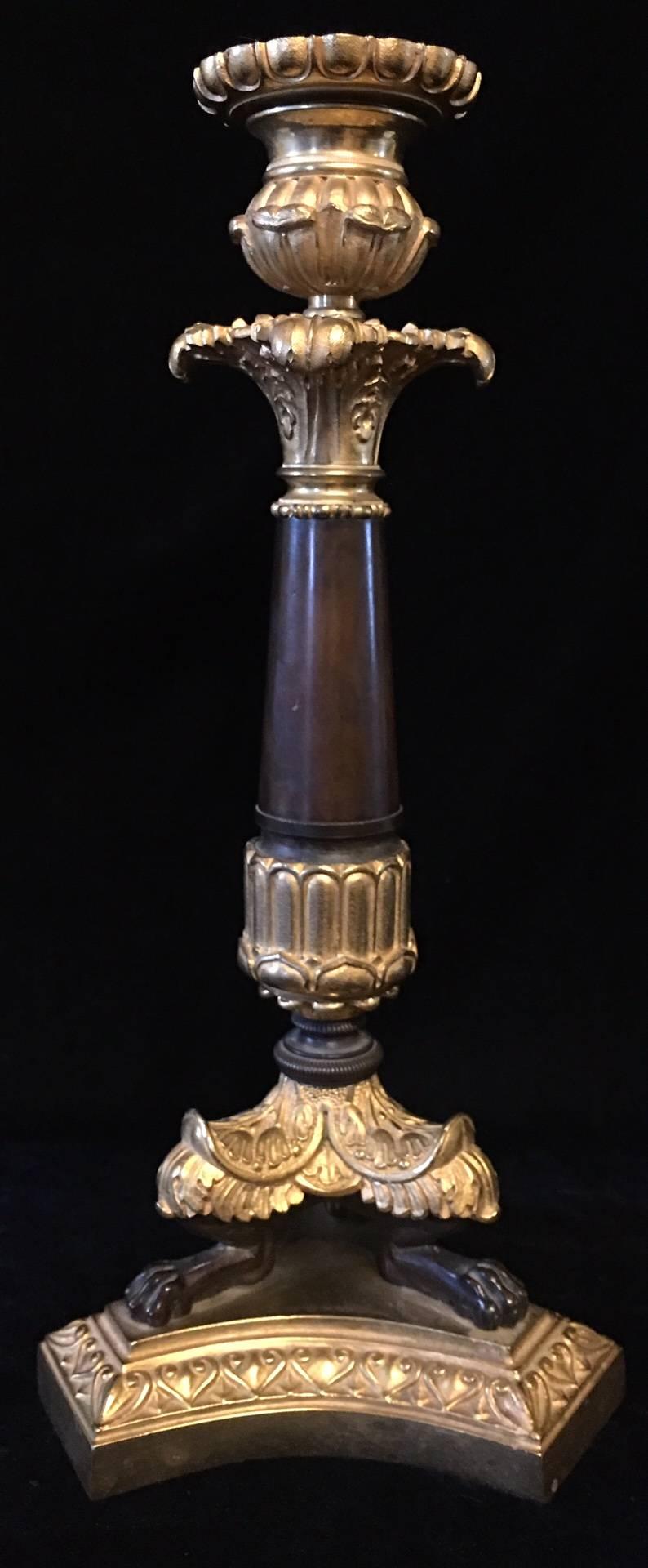 A pair of Napoleon III gilt bronze candlesticks, the cast Corinthian capitals supported on a tapered column terminating on three-lion paw feet.
    