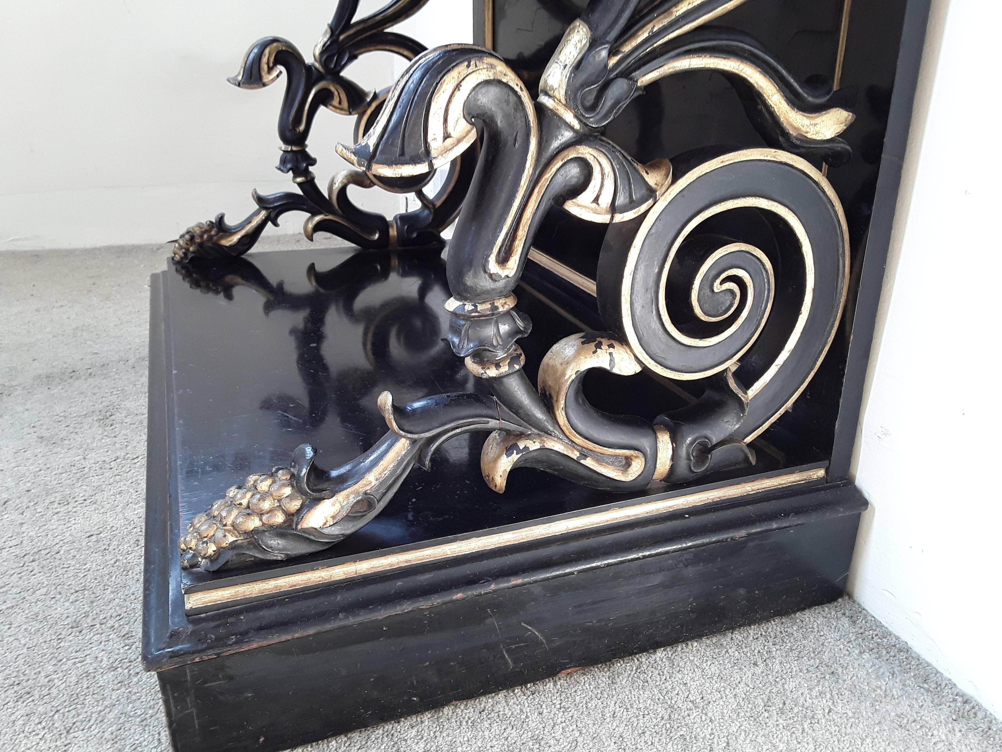 19th century ebonized and gilt enclosing shelves with a scrolled surmount and sides on a platform plinth base.

       