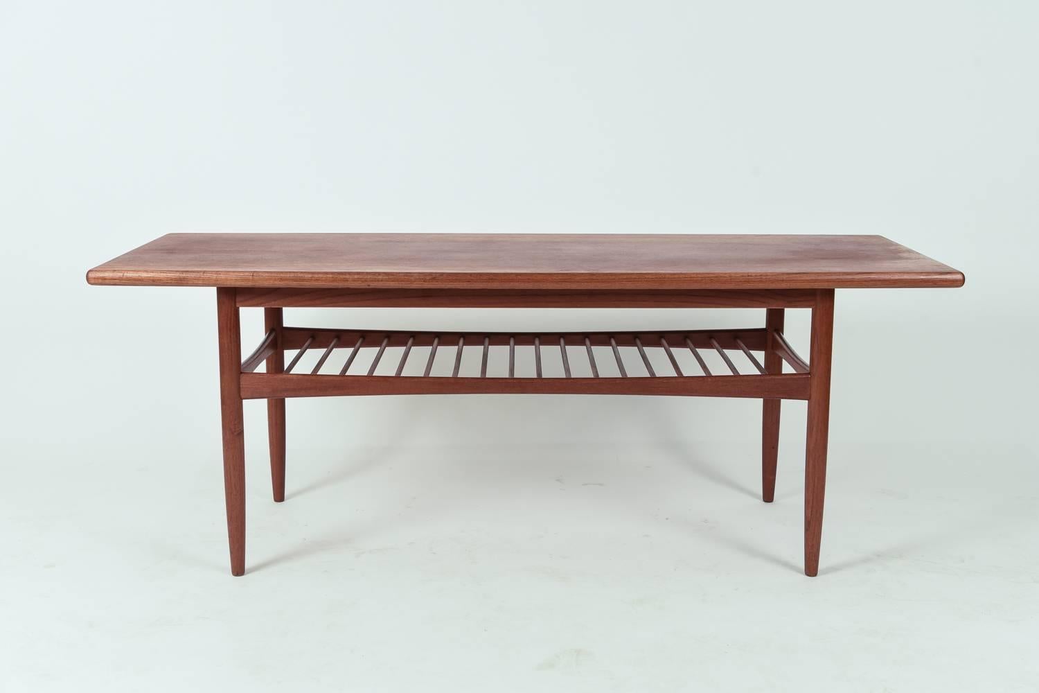 A Danish Mid-Century coffee table in the manner of Grete Jalk. Features a slatted shelf underneath.