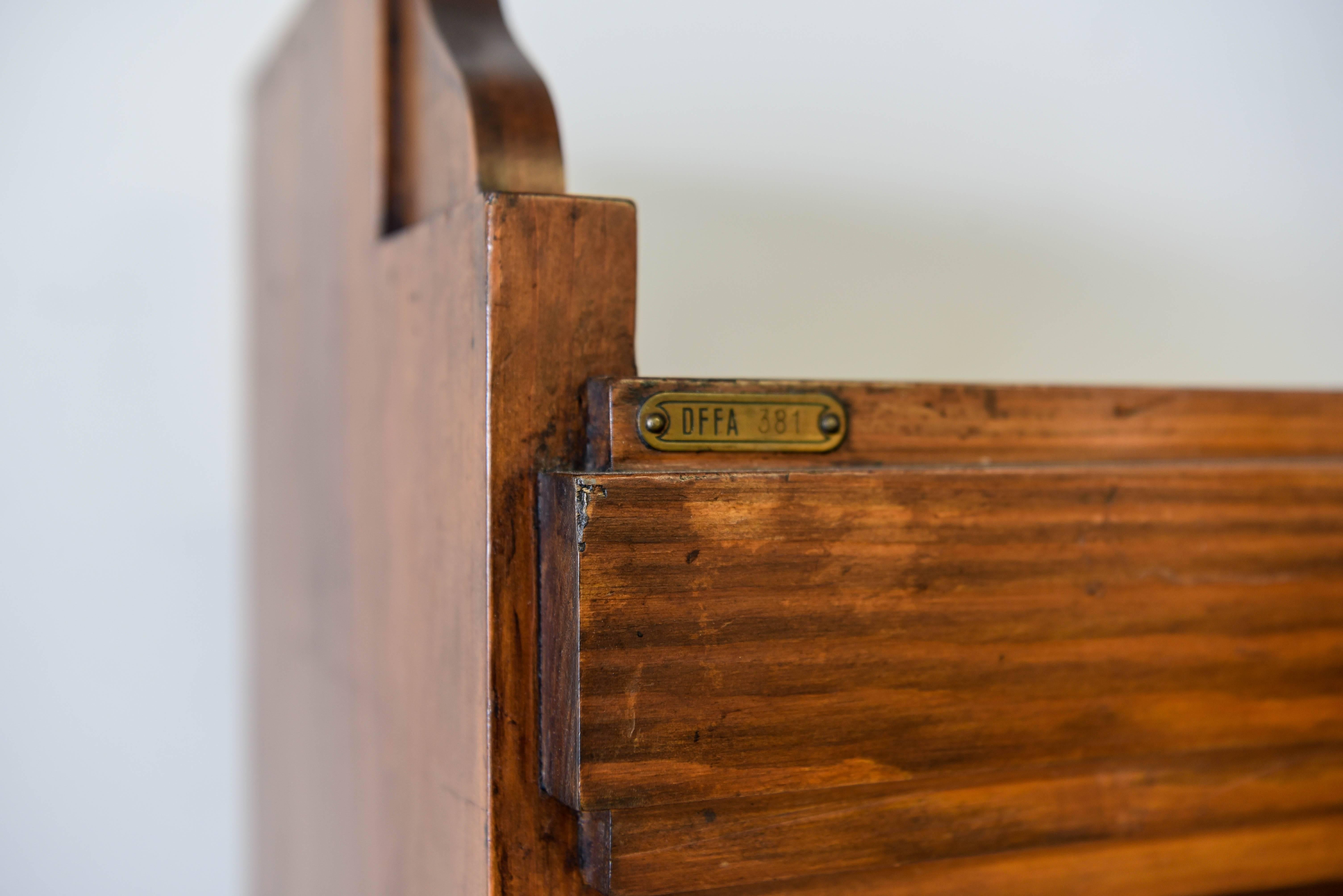 Stamped on back. 1930s stained Oregon pine. A very handsome, warm, and inviting piece of furniture, it looks great left open with books on the shelves, showing off the brass accents with the drop down hinges.