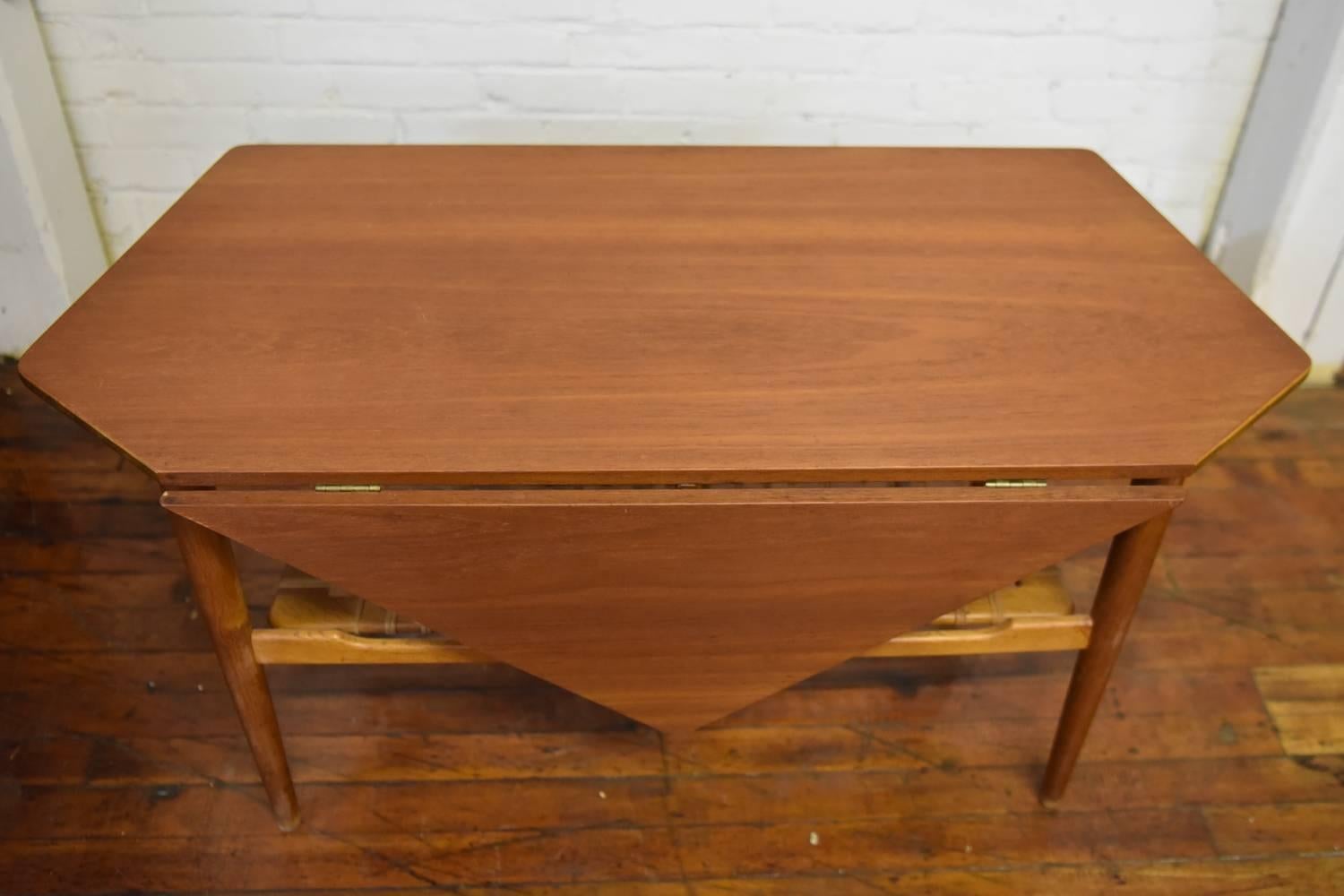 This beautiful teak coffee table is perfect for apartment living. With a drop leaf to add a little extra space during evenings of entertainment and a magazine rack underneath, this table works as storage and fills its purpose of a cocktail/coffee