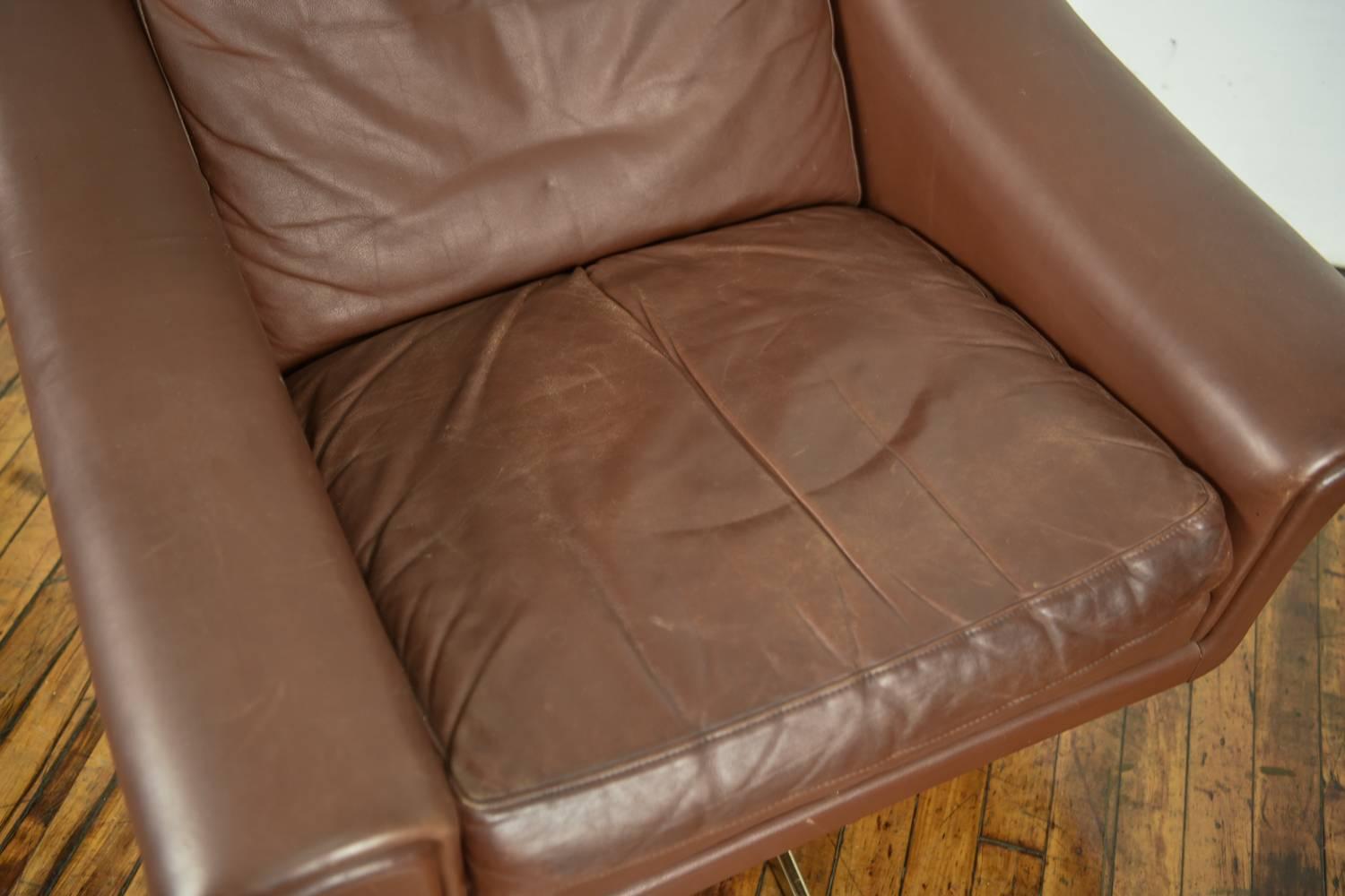 High back 'Ambassador' lounge chair designed by Aage Christiansen in the mid-1960s and produced by Erhardsen & Andersen, Denmark. Upholstered in supple chocolate brown leather on a steel swivel base. Super elegant OG highest quality with care