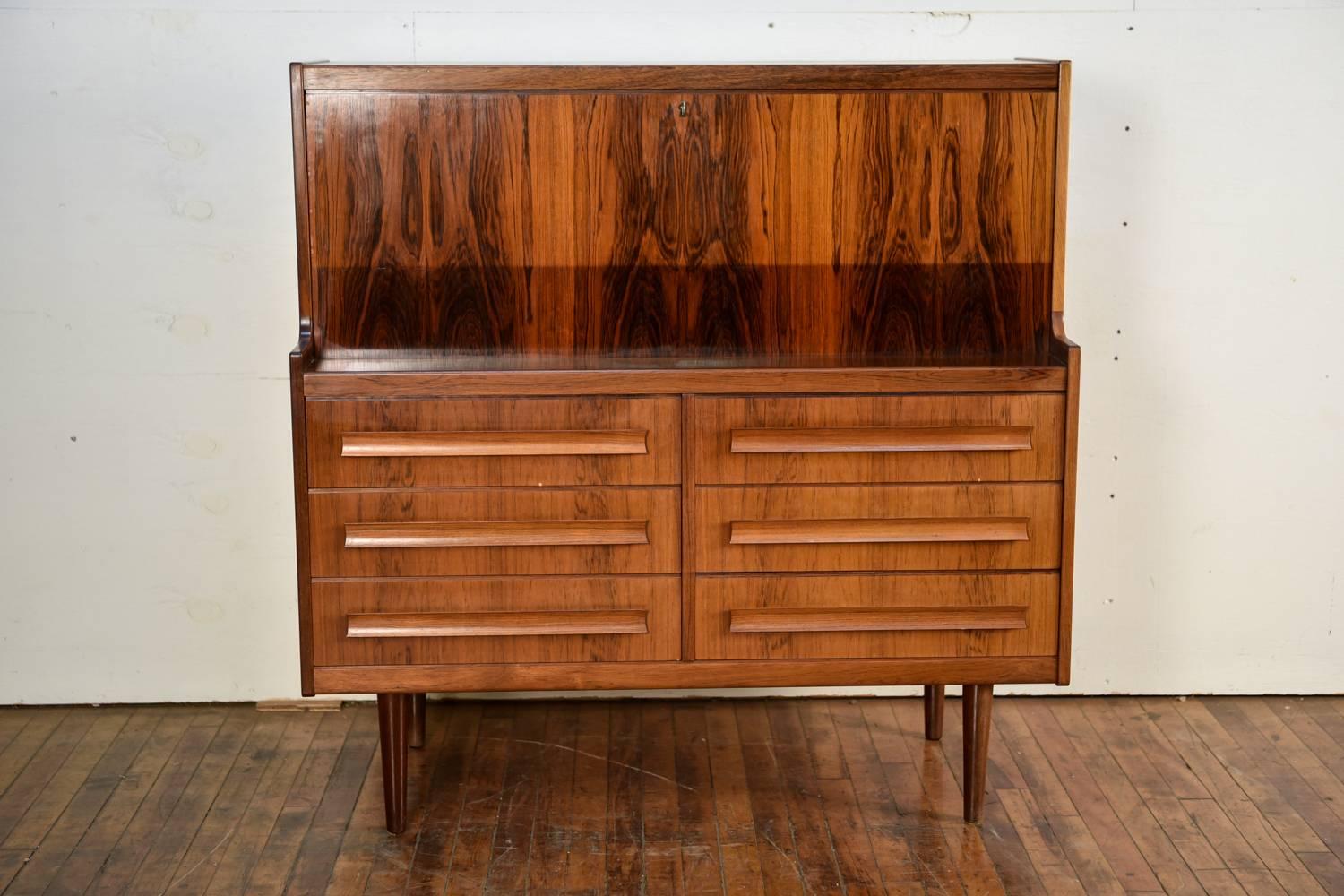 This stunning secretary or secretaire was manufactured by Ørum Møbelfabrik, circa 1950s. Absolutely gorgeous rosewood with a fantastic color and grain. Great drawers for storage purposes with stylish handles. Top portions opens up to reveal more