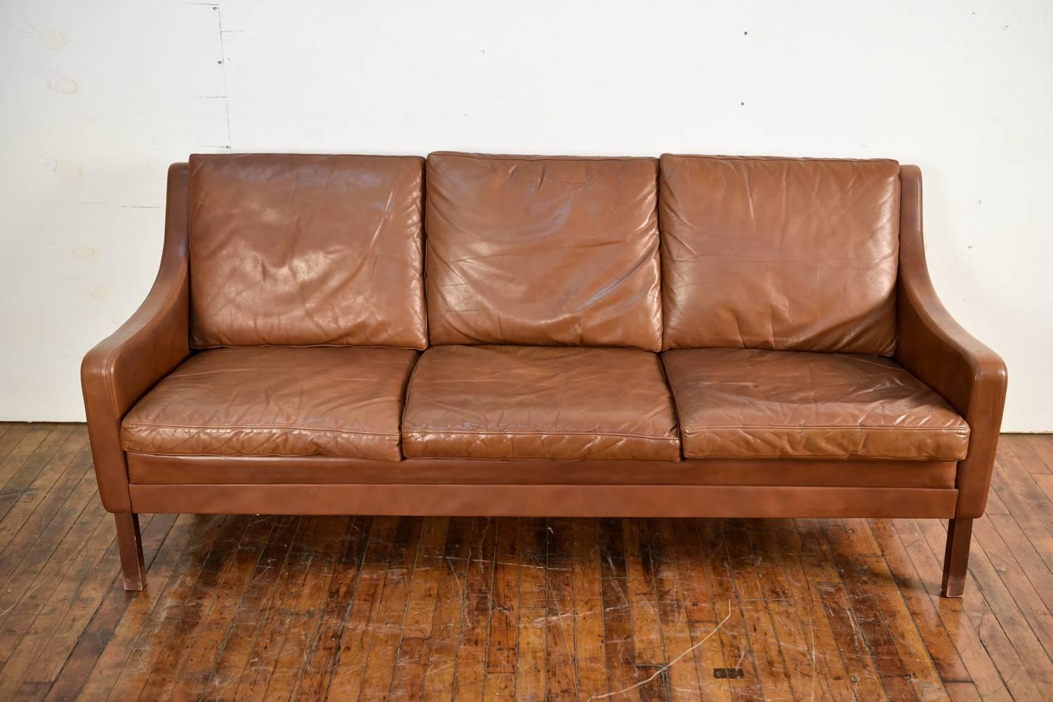 This Danish midcentury sofa is in the manner of the iconic designer Børge Mogensen. Great leather with attractive vintage wear.