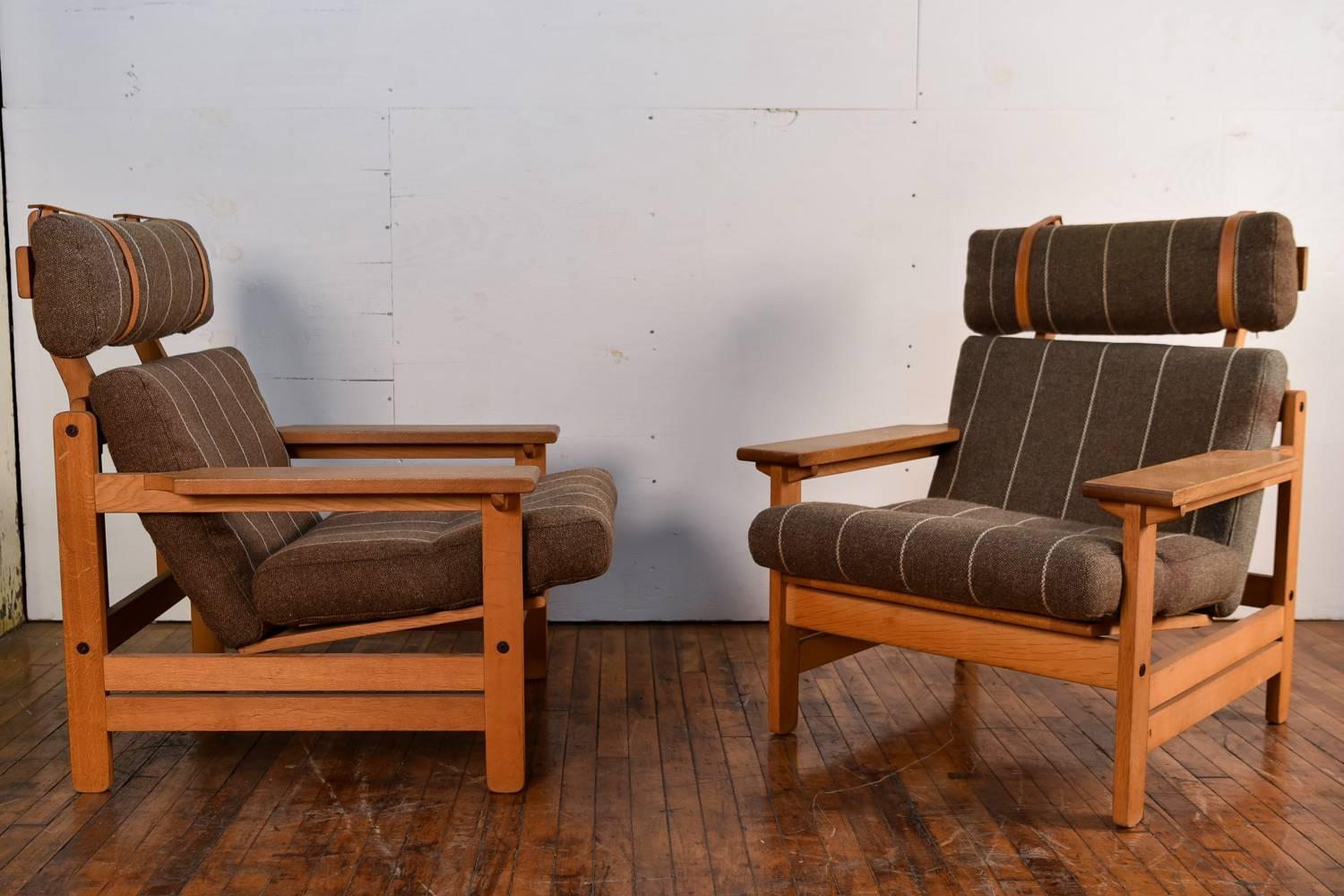 A great pair of Danish midcentury lounge chairs designed by Aksel Dahl for K.P. Møbler in 1972. These chairs feature frames of oakwood, with paddle like arms, enhancing the comfort. The headrest cushion is held into place with stylish straps,