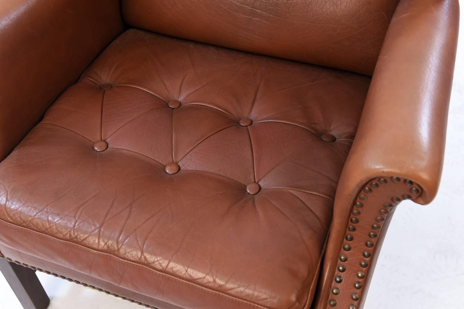 This chair is elegant from every angle. Upholstered in stunning cognac leather featuring a tufted back and seat and studded edges. A classic wingback form with even more elements of design interest.