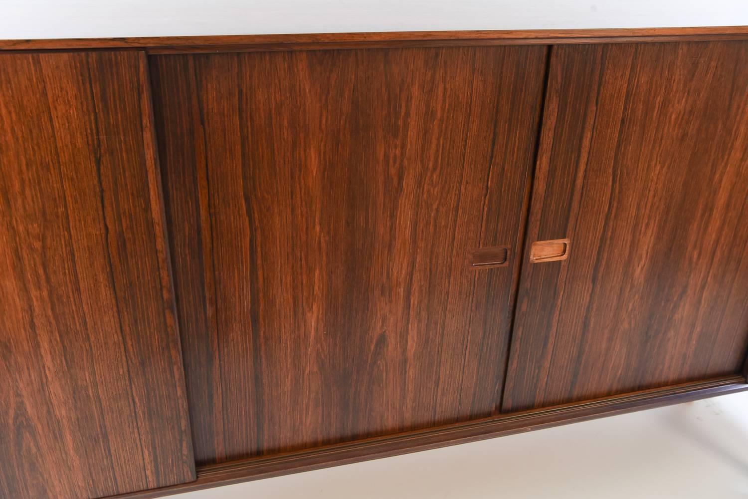 This sideboard by Arne Vodder features stunning rosewood with a beautiful grain and color. Small recessed handles adorn the sliding doors.